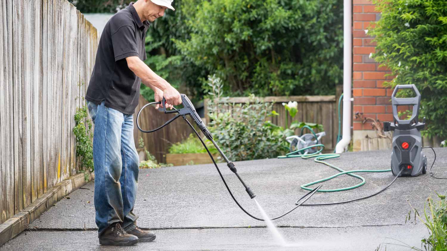 Man cleaning concrete driveway