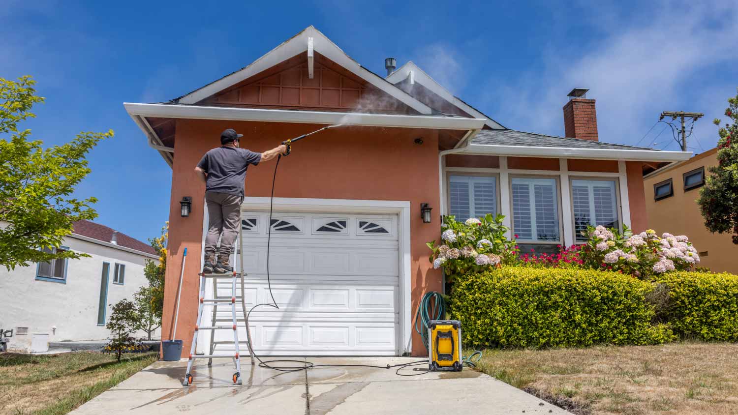 Man power washing a home