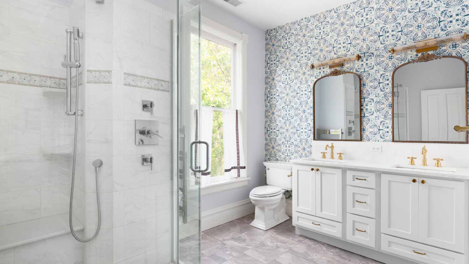 A bathroom with gold faucets and blue wallpaper