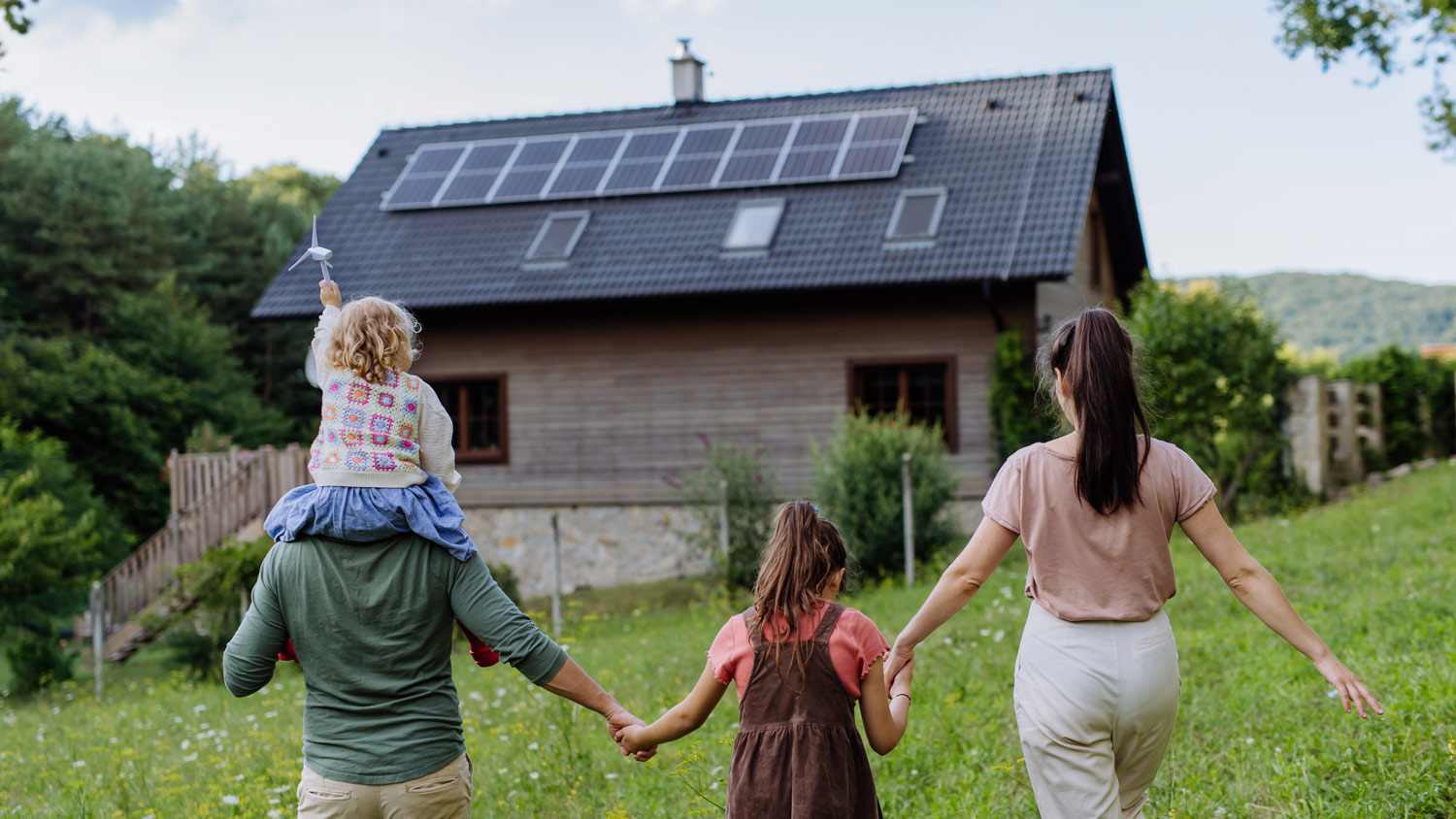 Family in front of family home with solar panels on the roof