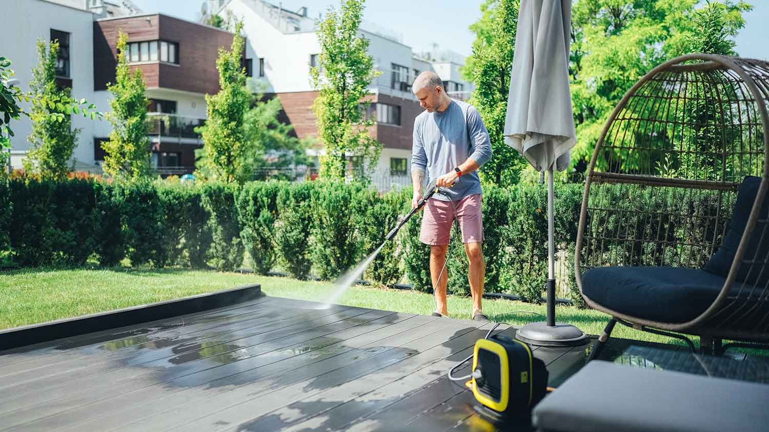 Man using electric power washer to clean a patio deck