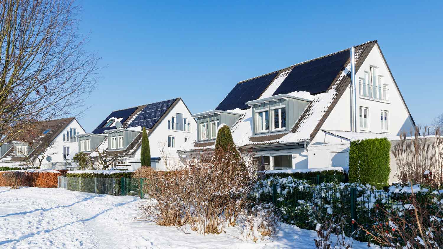 A house with solar panels on the roof on a snowy day