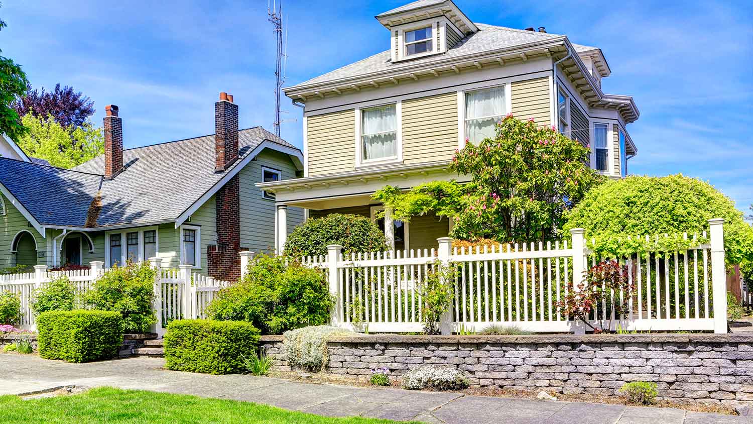Two story suburban house with a white wooden fence