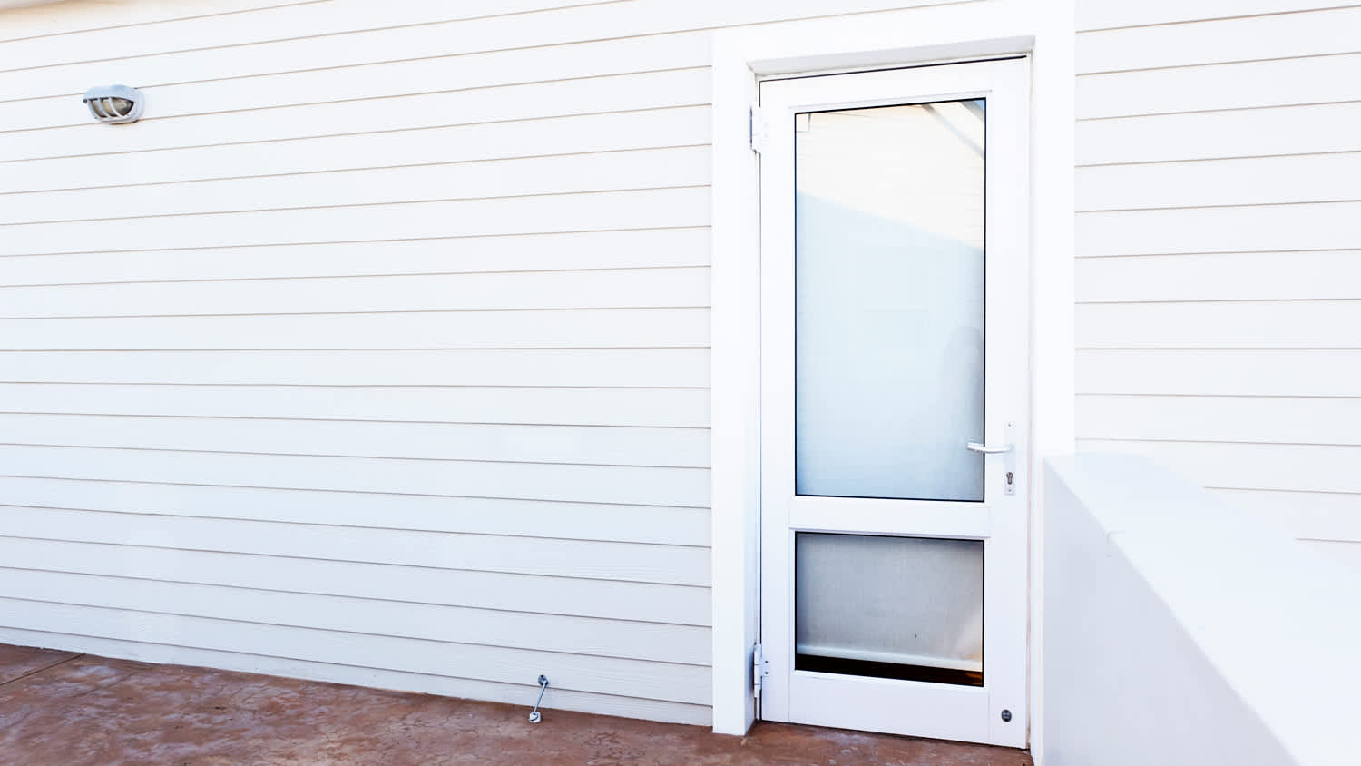 Outside wall and glass door of white painted clapboard house