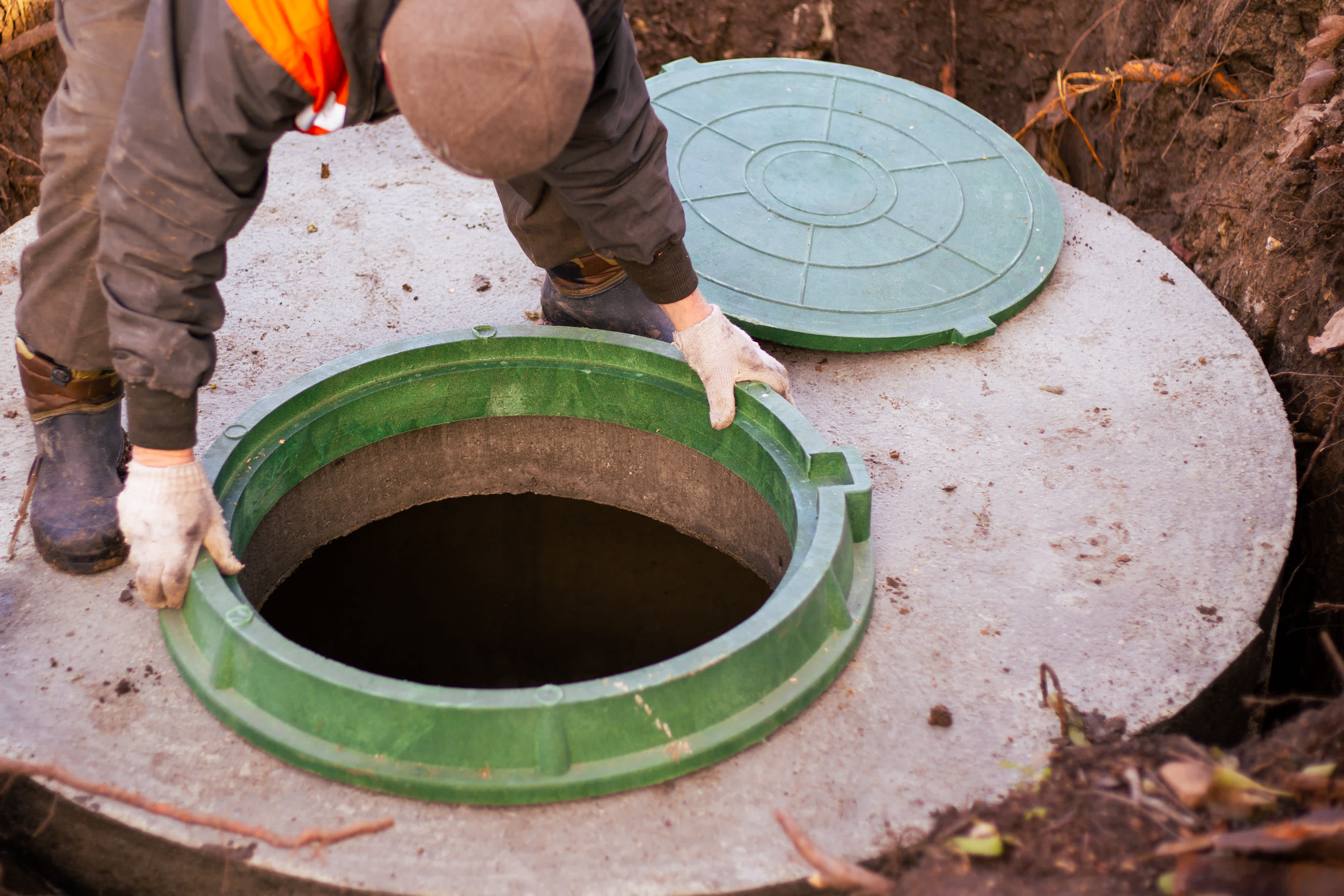 Worker installing a manhole during septic system repair to maintain proper drainage and waste management