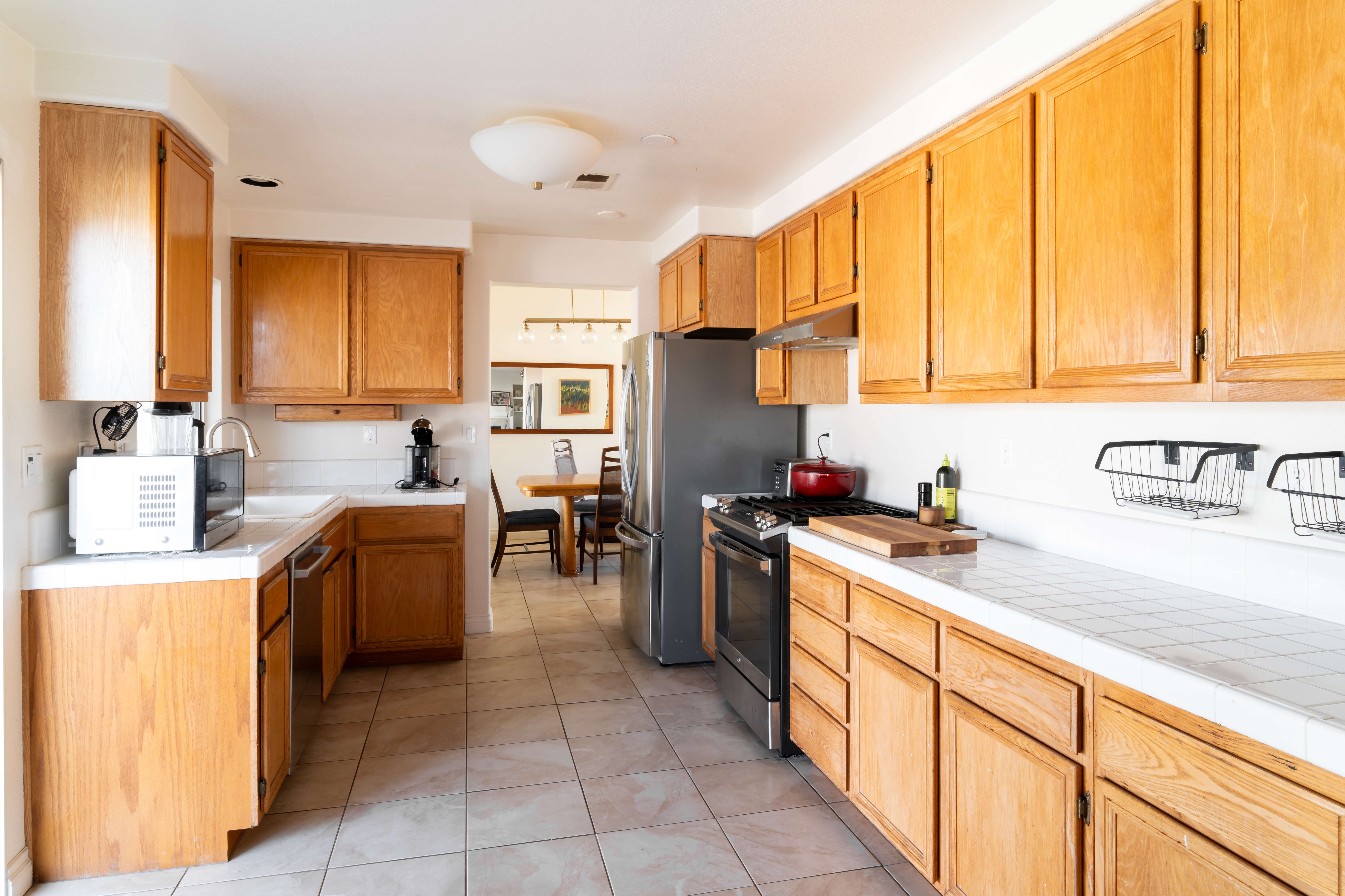 Full kitchen when wood cabinets and white tile countertops