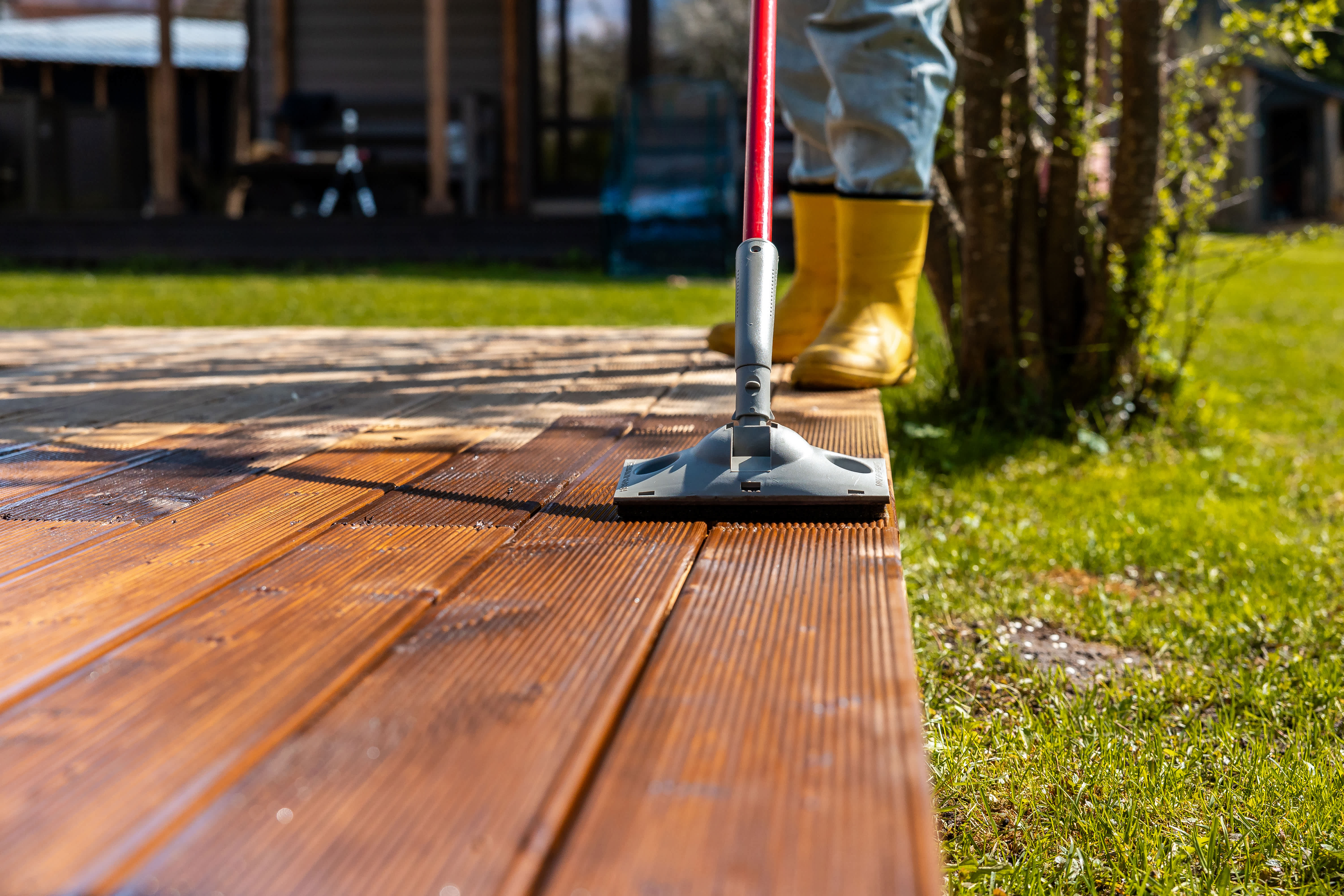 Worker applying stain to a wooden deck