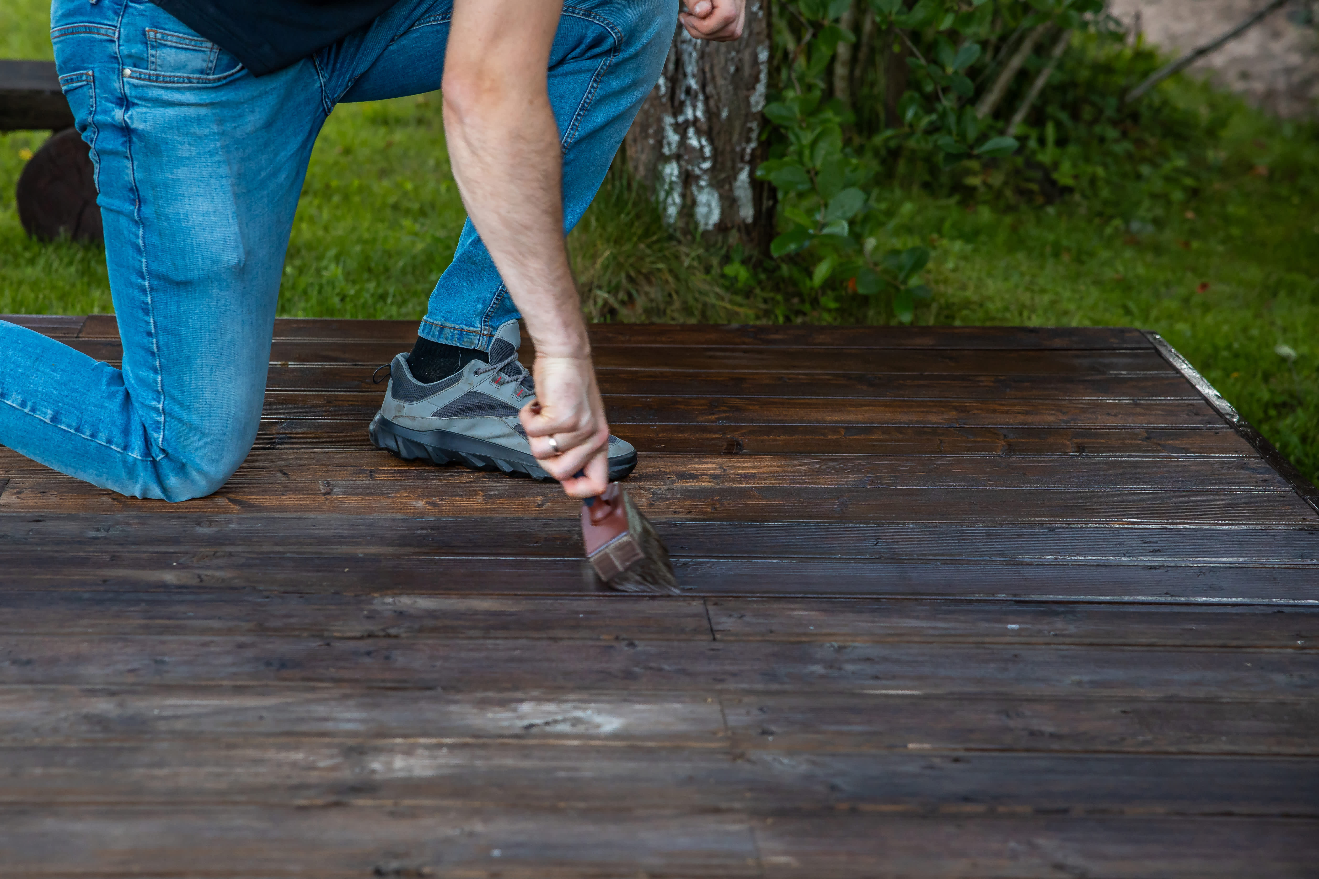 Person applying stain to a wooden deck