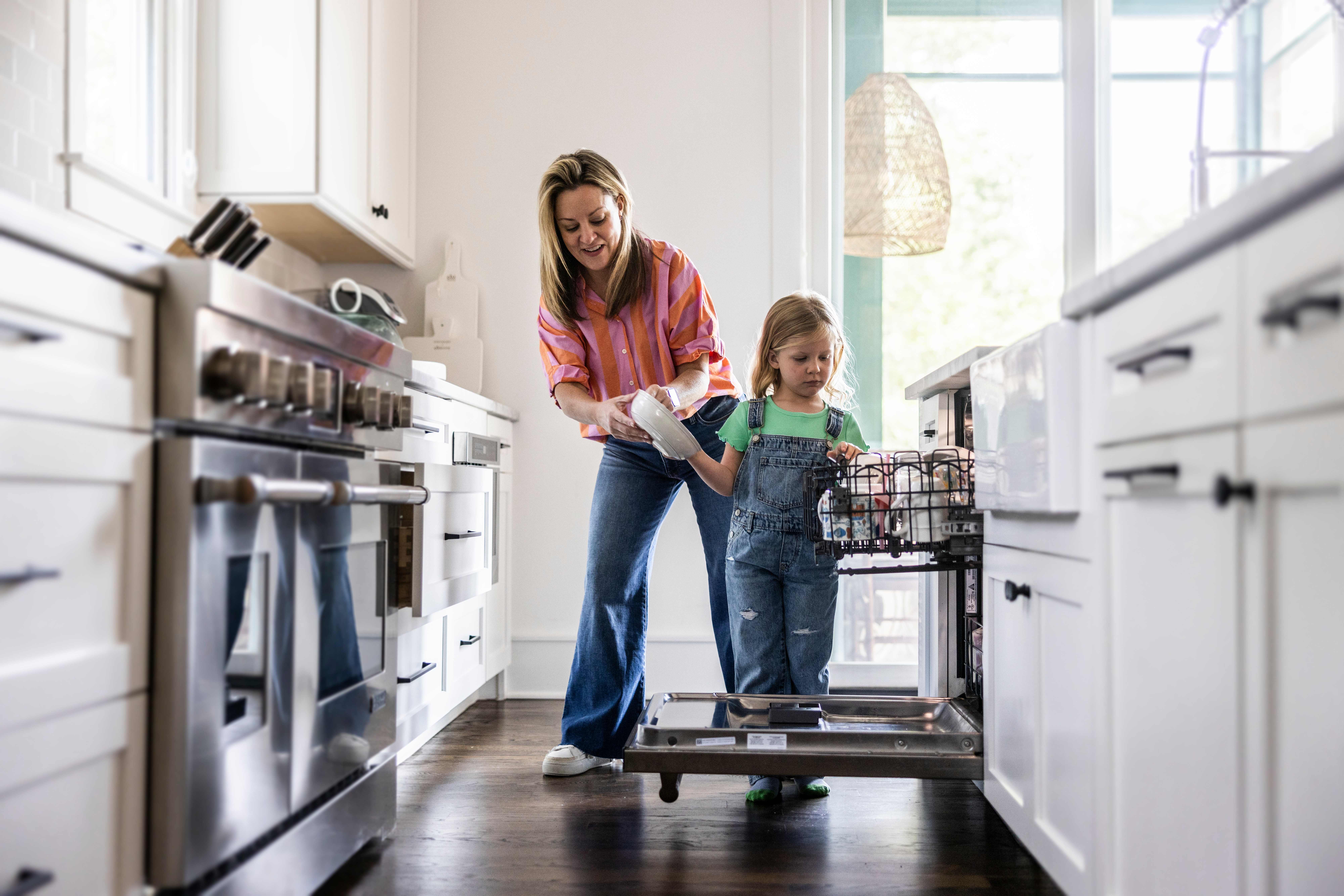 Mother and daughter loading dishwasher
