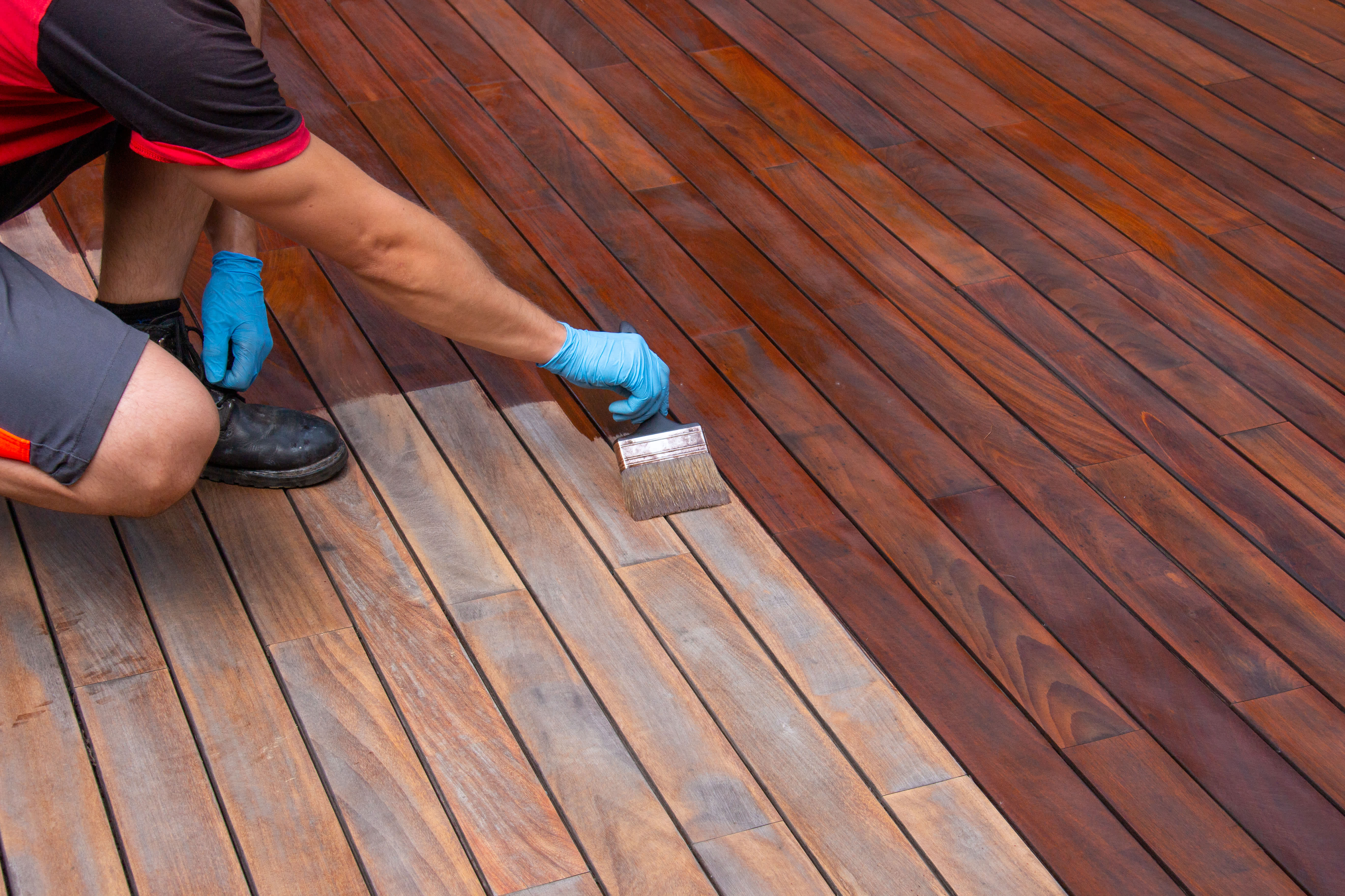 Handyperson using a brush to stain a wooden deck