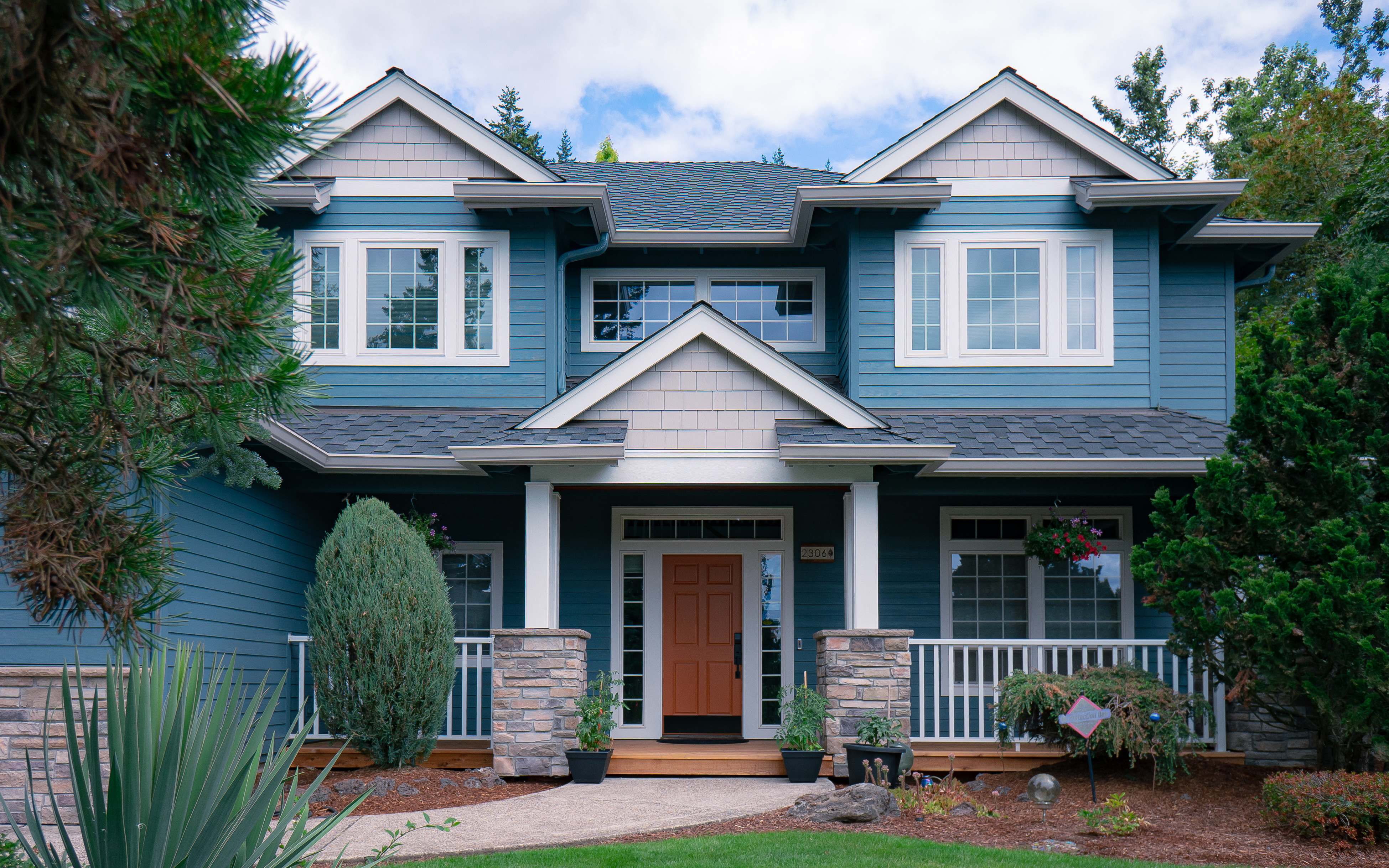 Two-story house painted blue with an orange door in Portland, OR