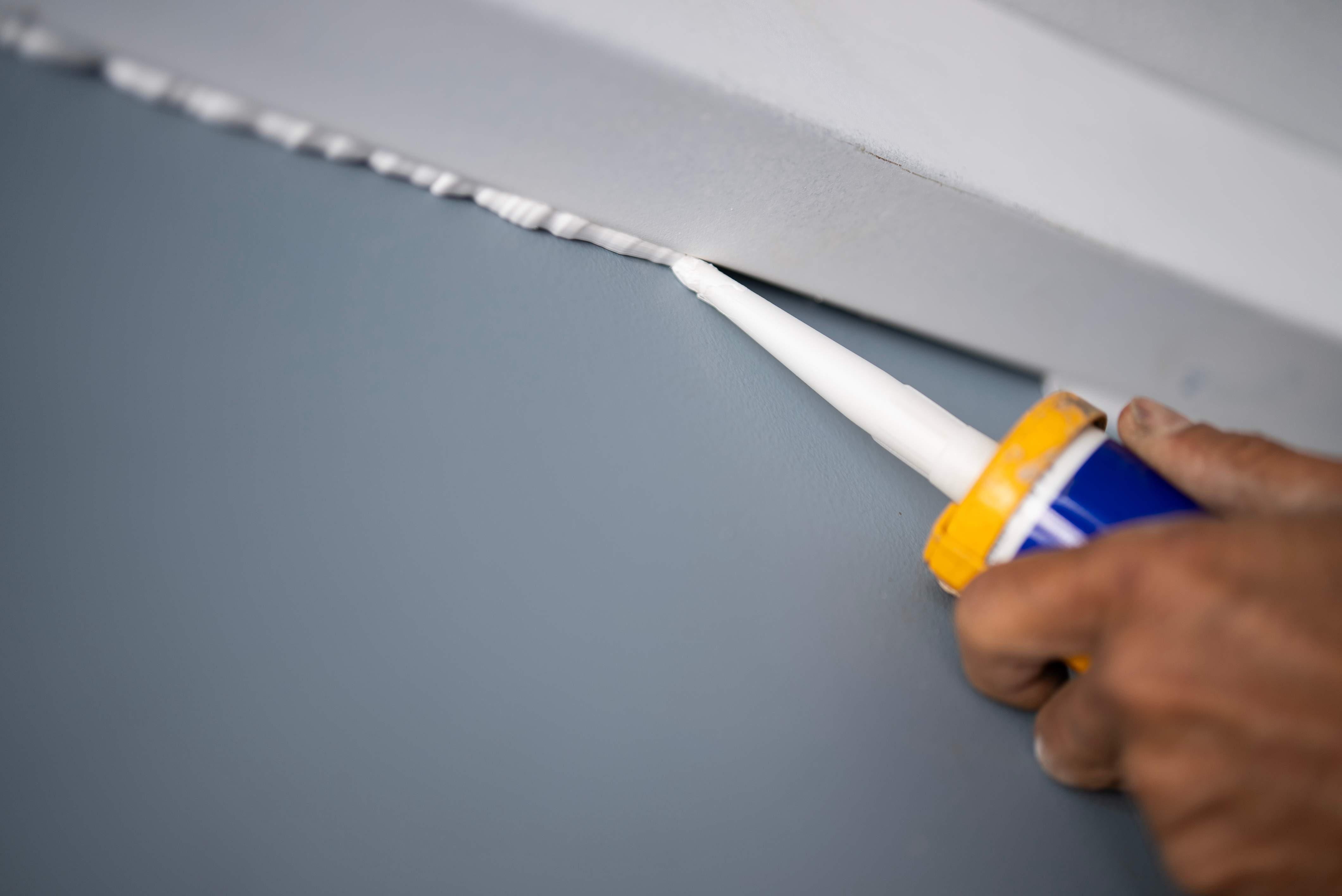 A person caulking a wall corner