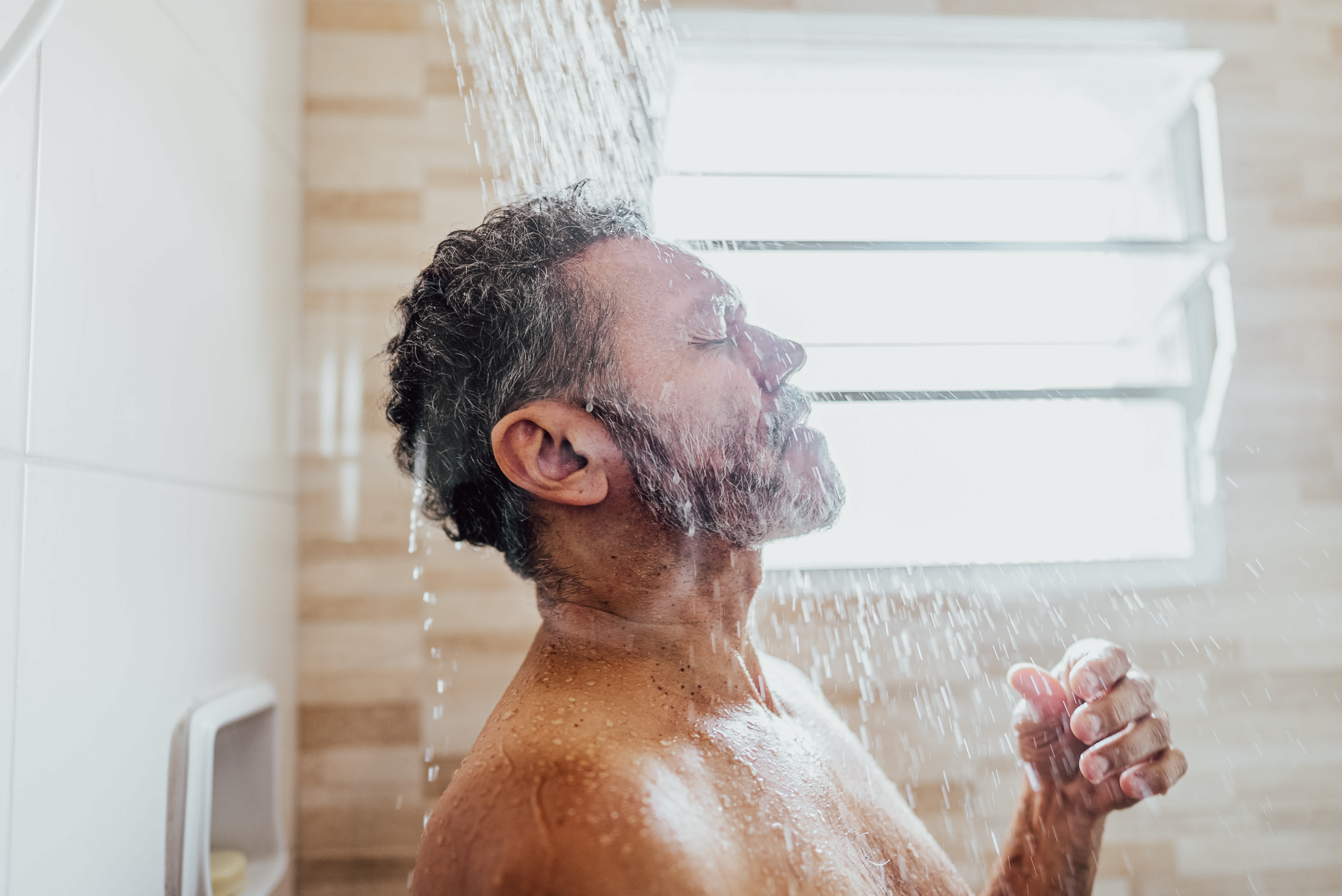 Mature man taking a shower in the bathroom
