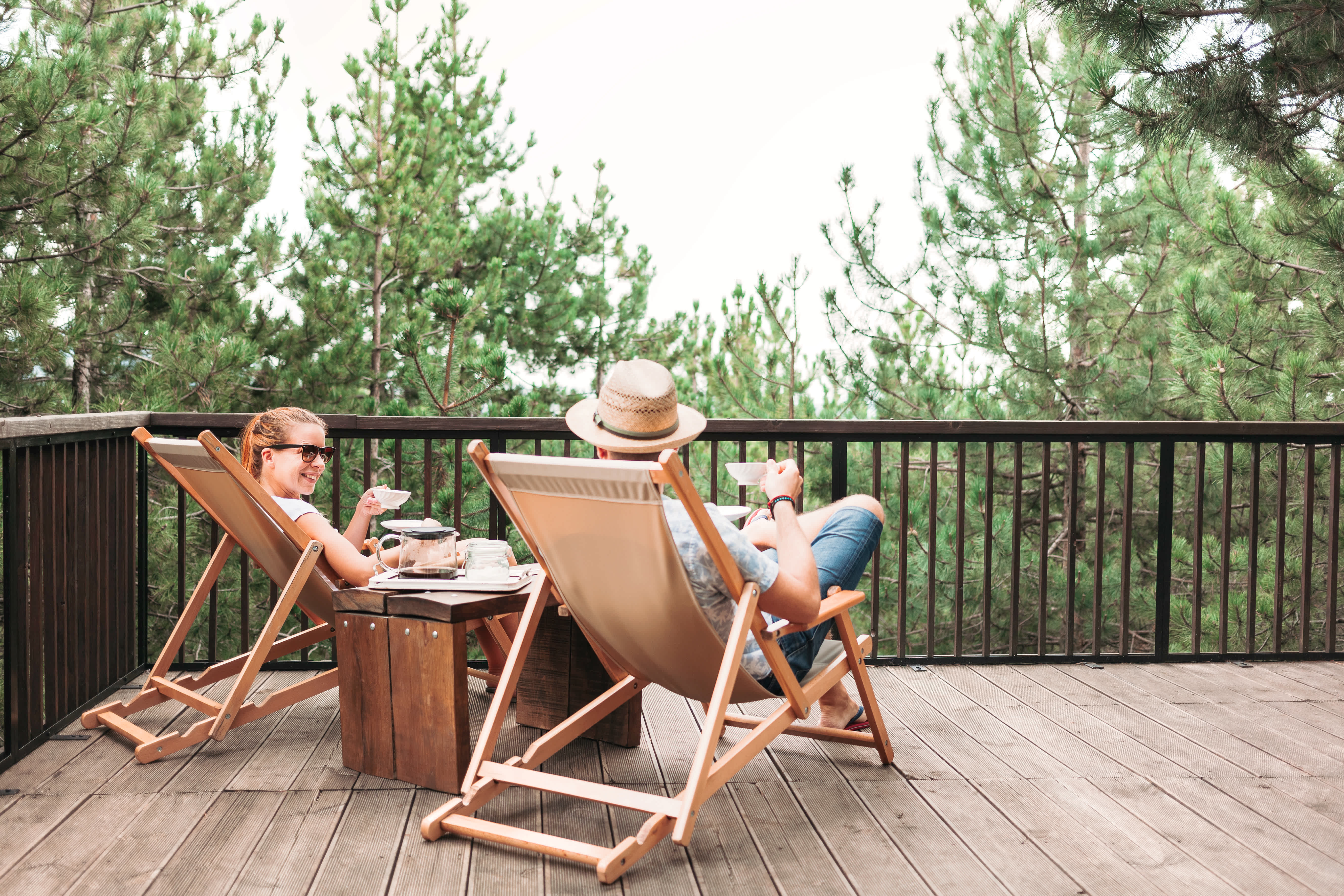 A couple sitting on a wooden deck enjoying coffee
