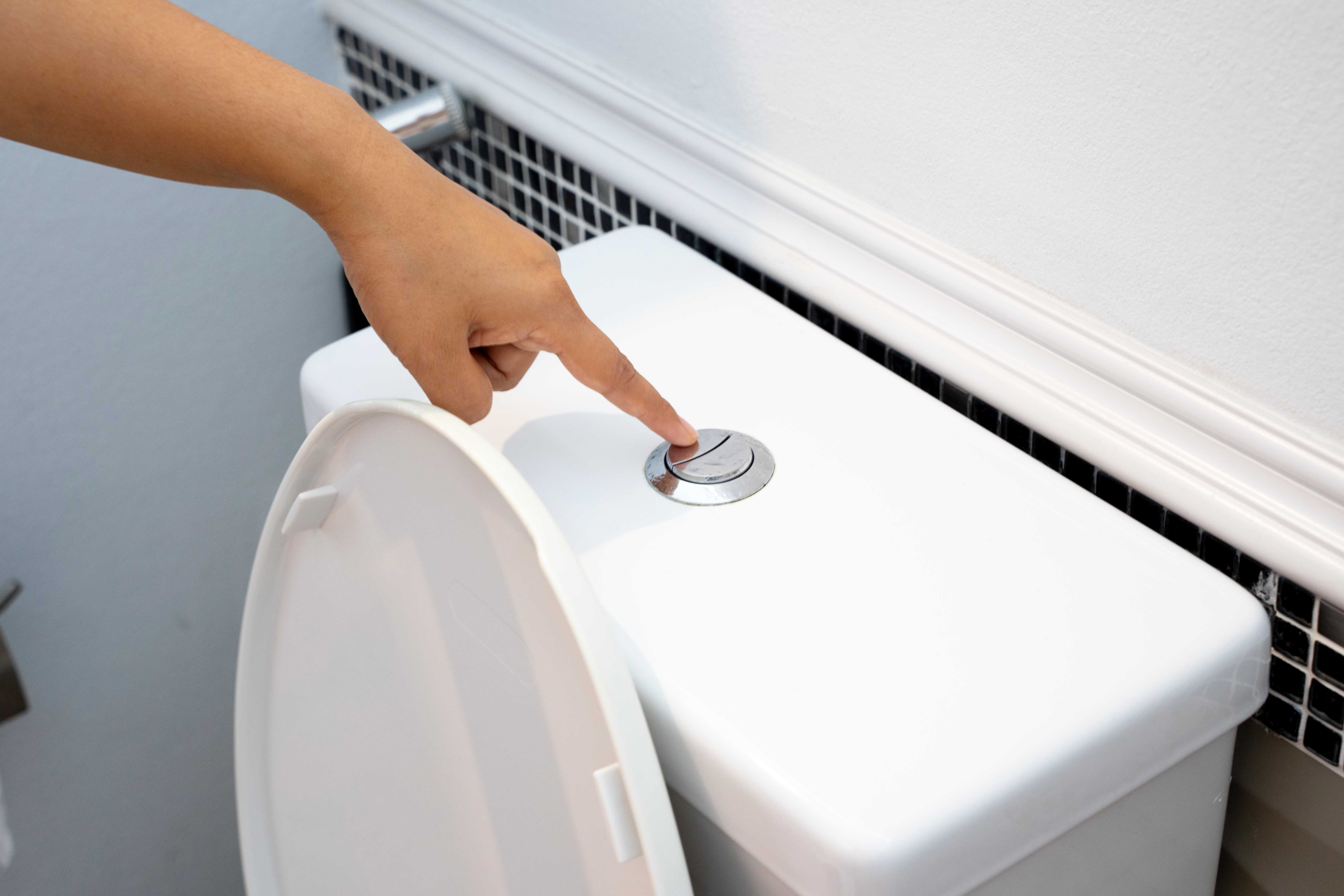 Person flushing a dual flush toilet