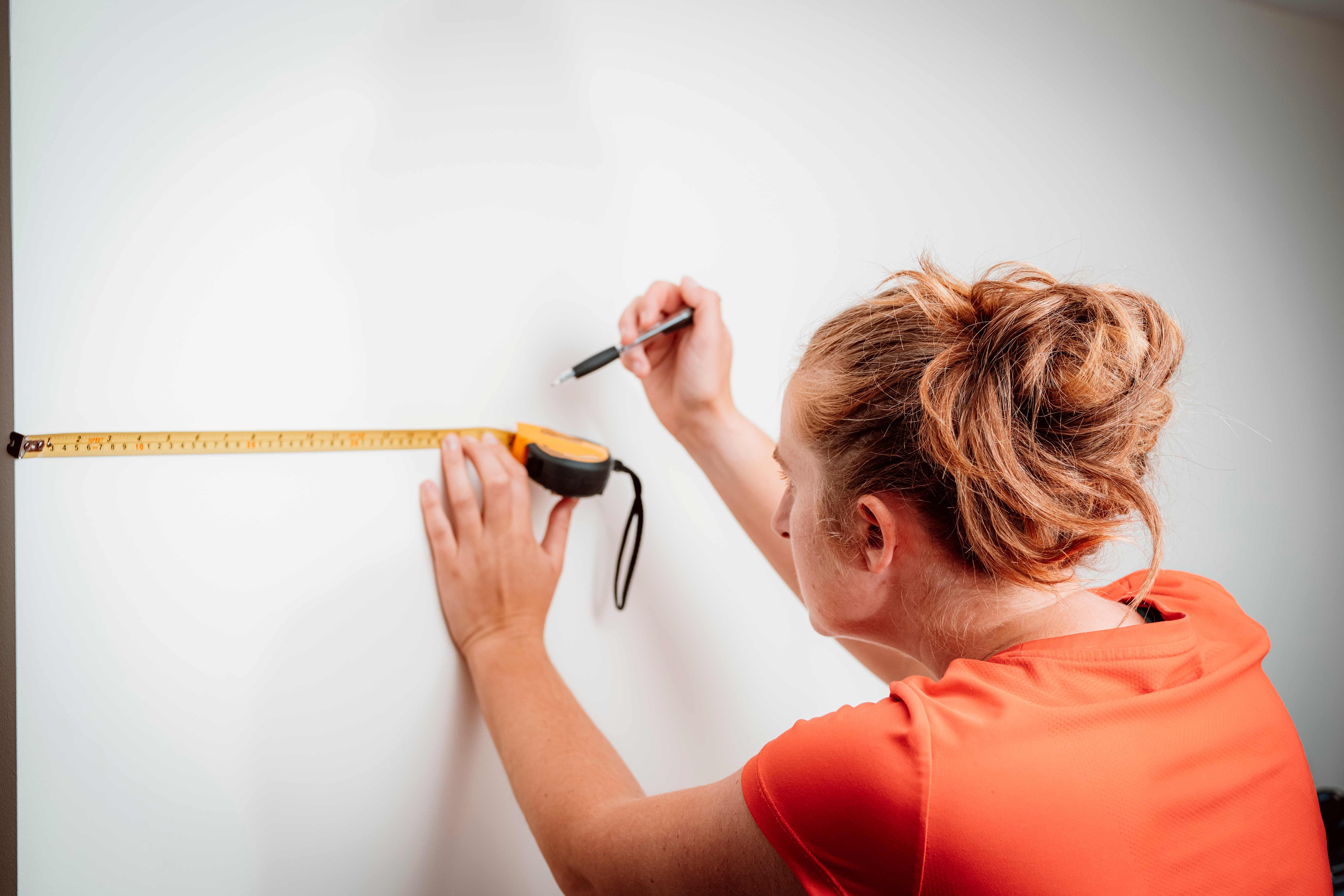 Woman using a tape measure to mark a spot