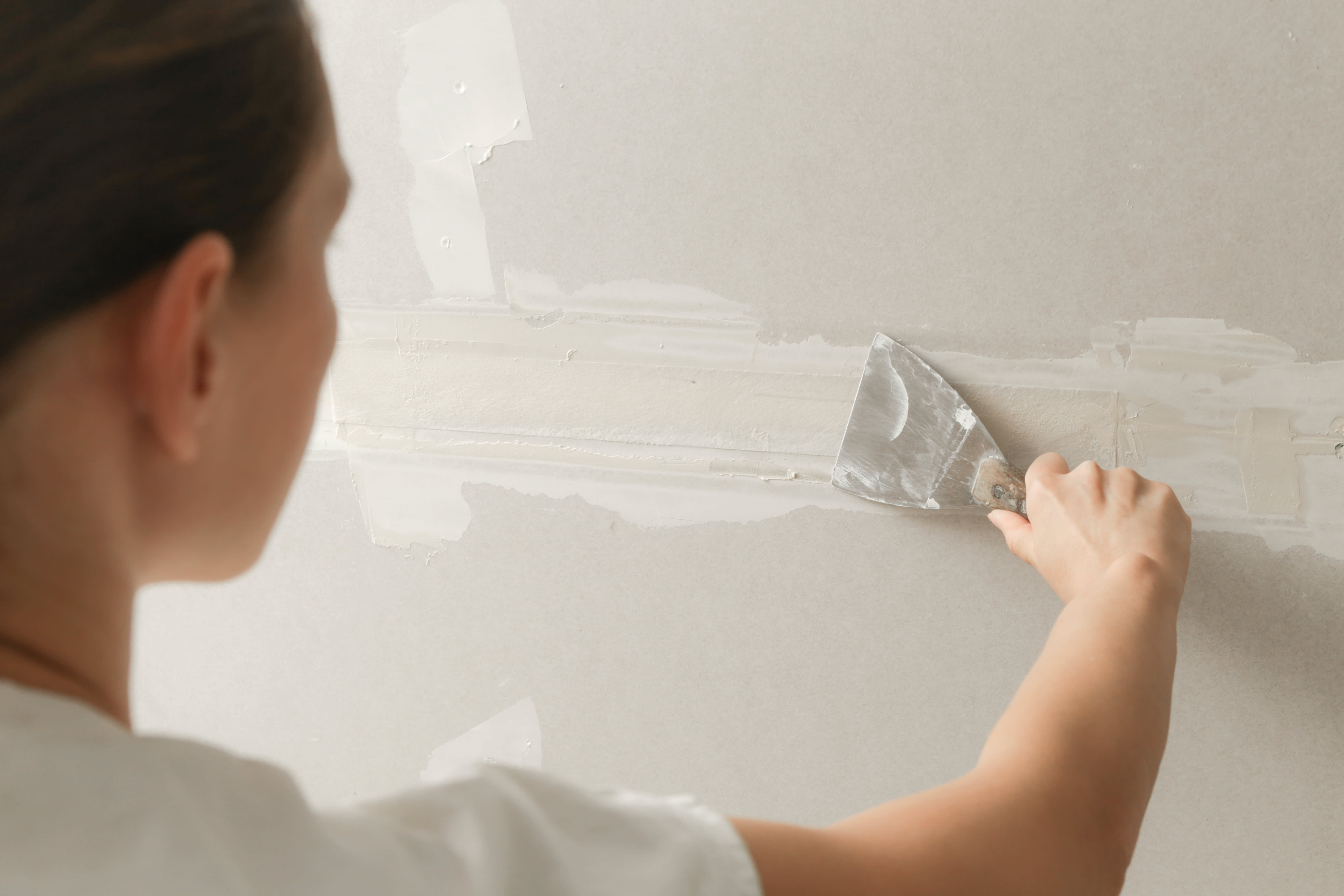 A woman mudding a drywall