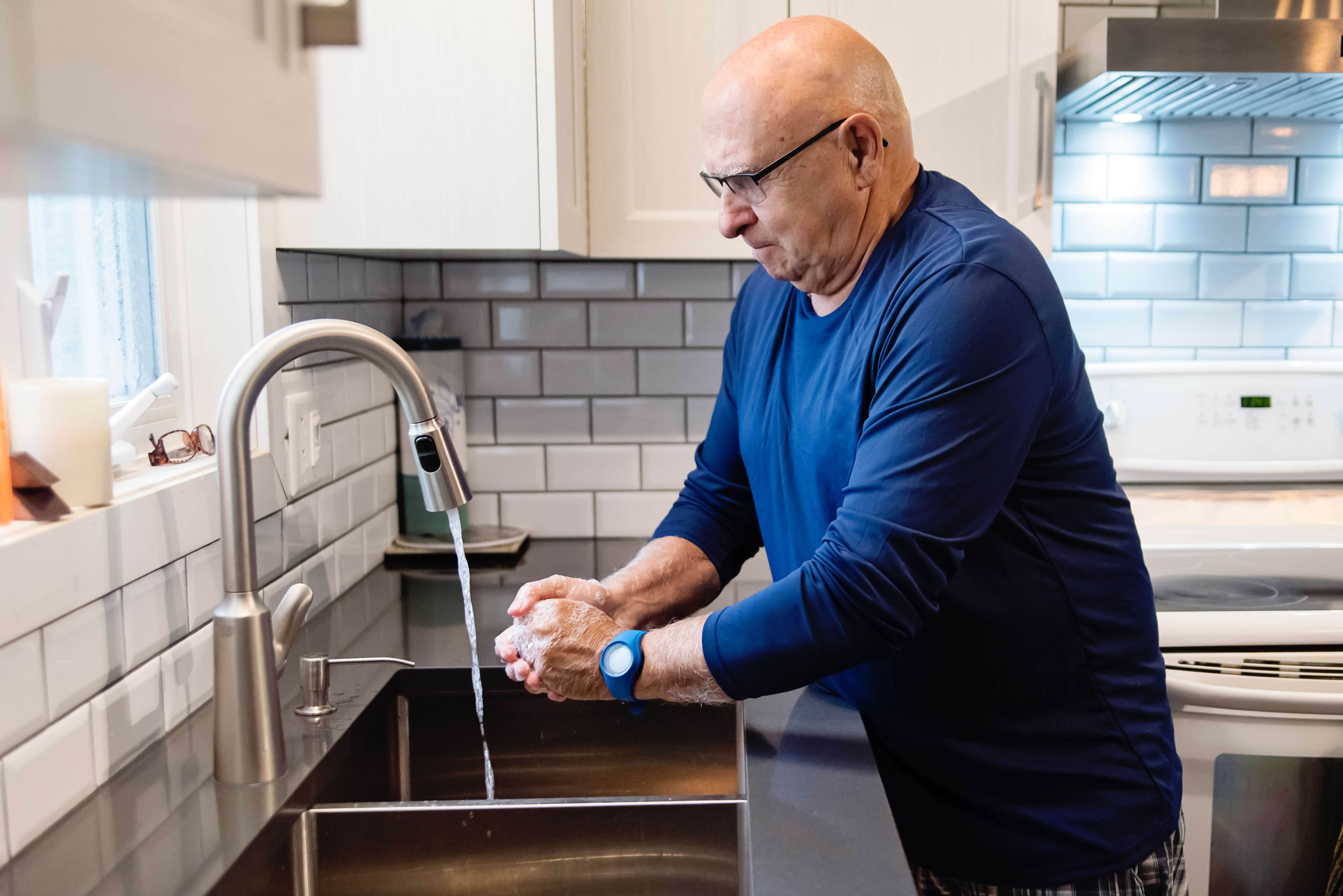 Senior man washing hands in the kitchen sink