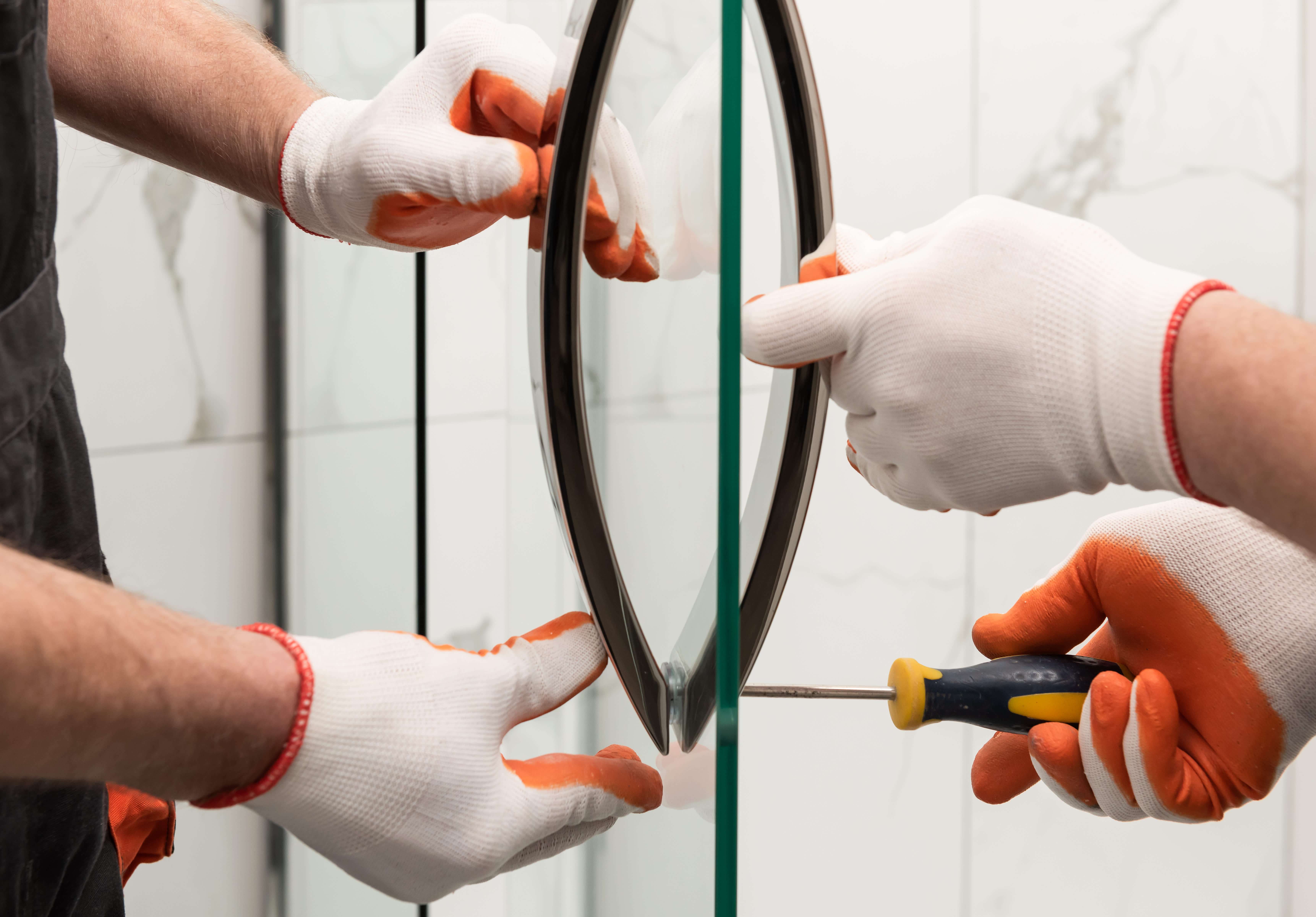 Workers mounting door handles on a glass shower door