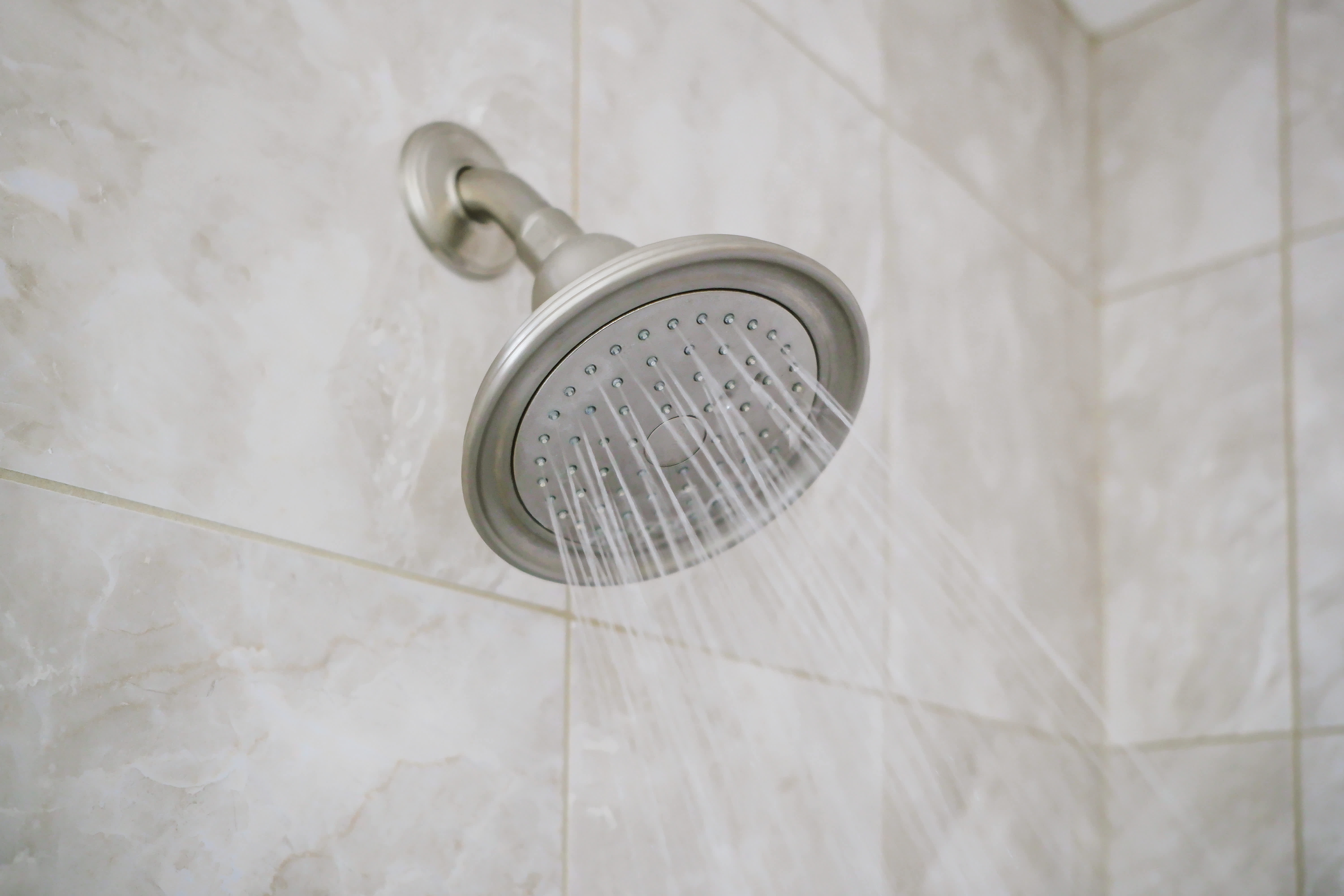 Shower head mounted to the wall with gray tiles