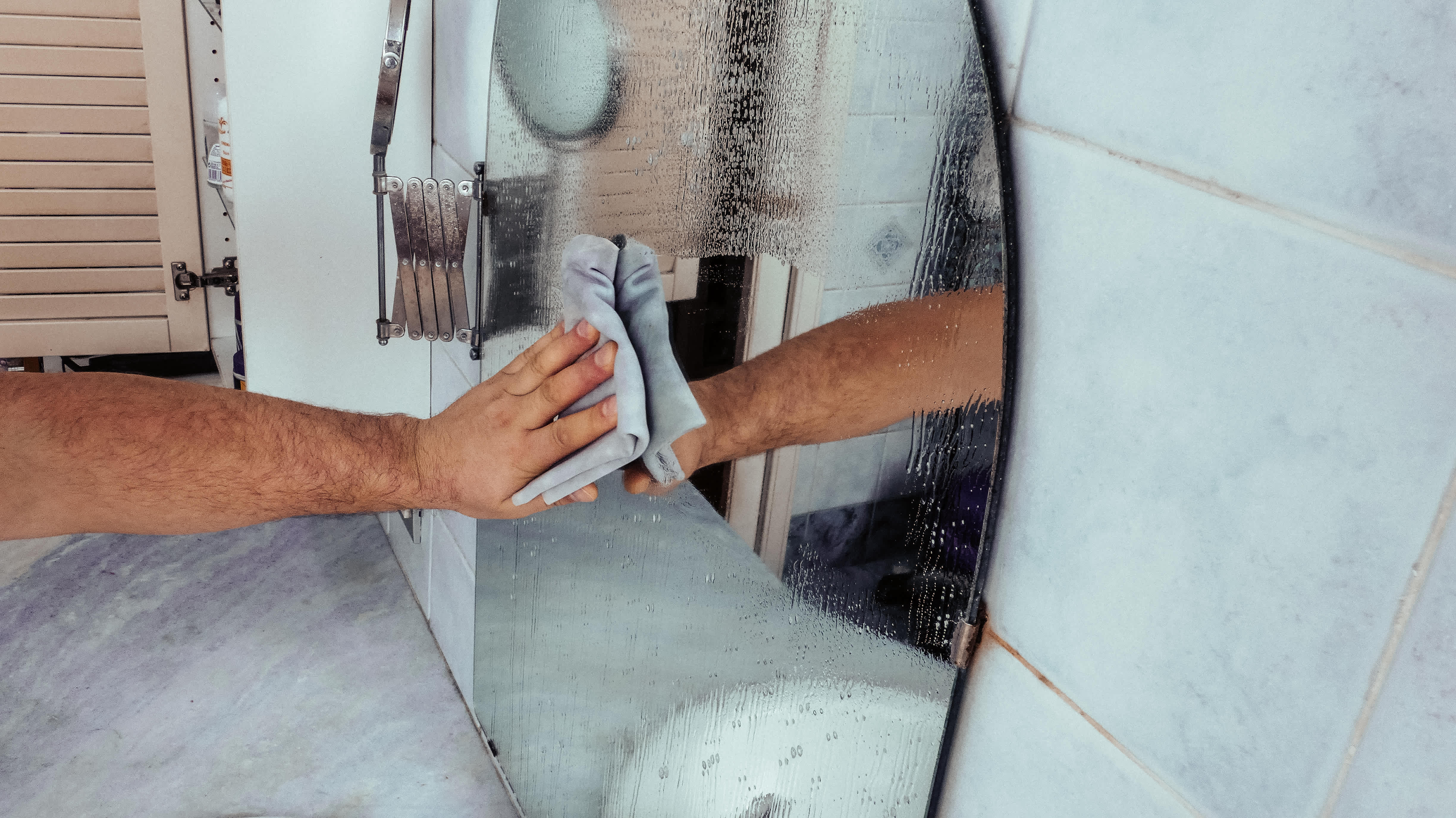 Close up photo of man hand cleaning a mirror.