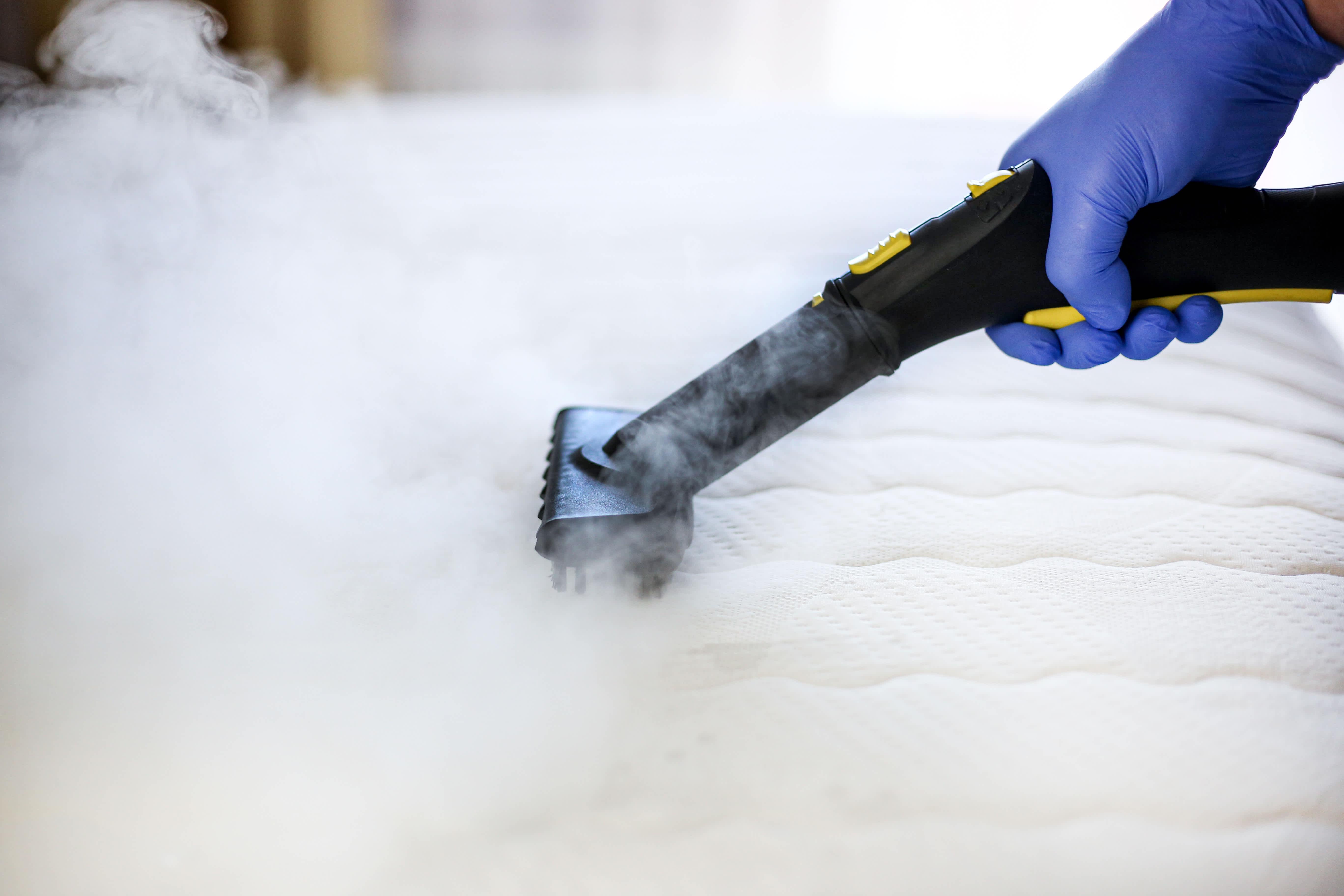 Person using a steamer to clean a mattress