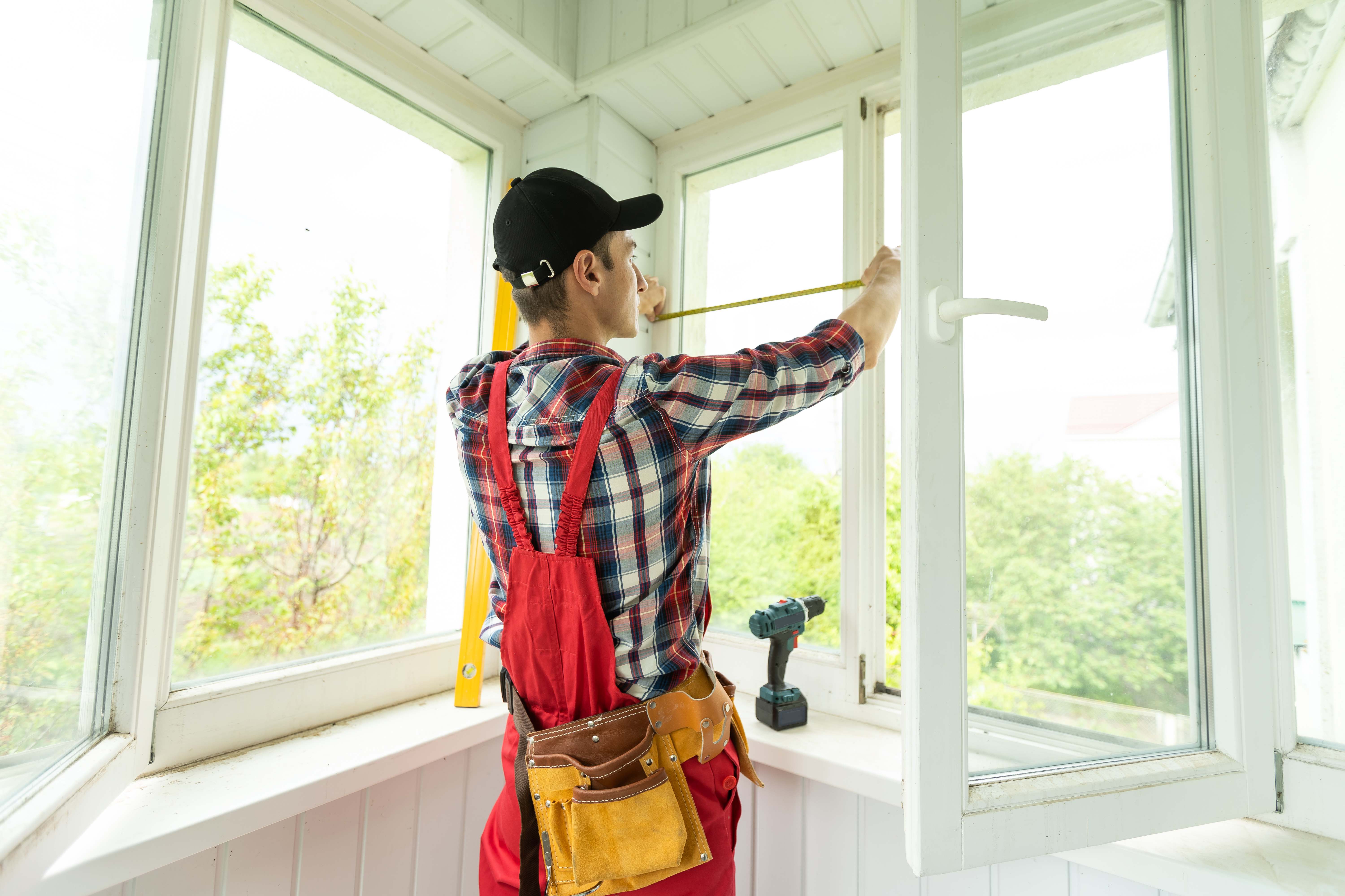 Contractor using a measuring tape to measure the windows