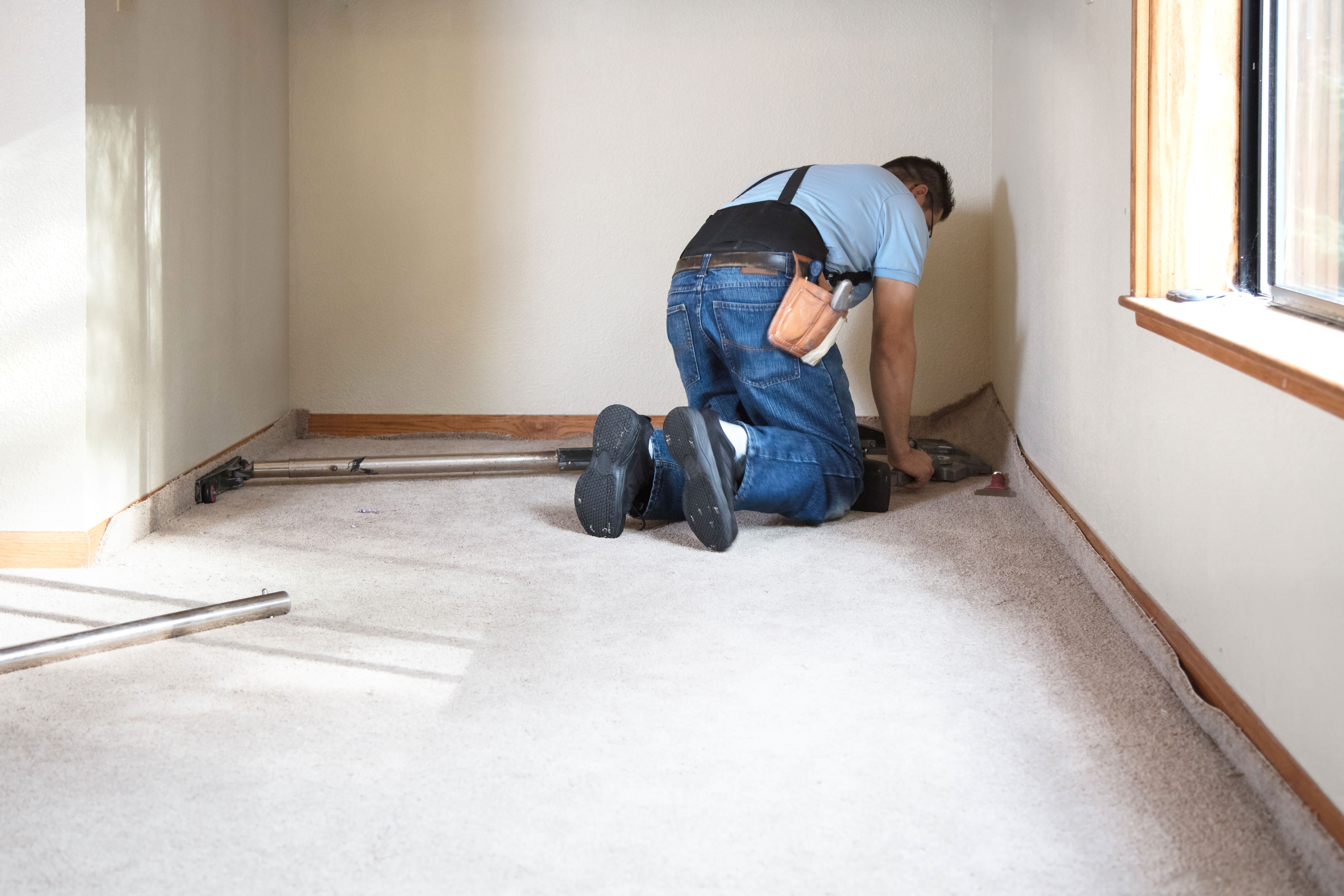 A professional installing new carpet in the room