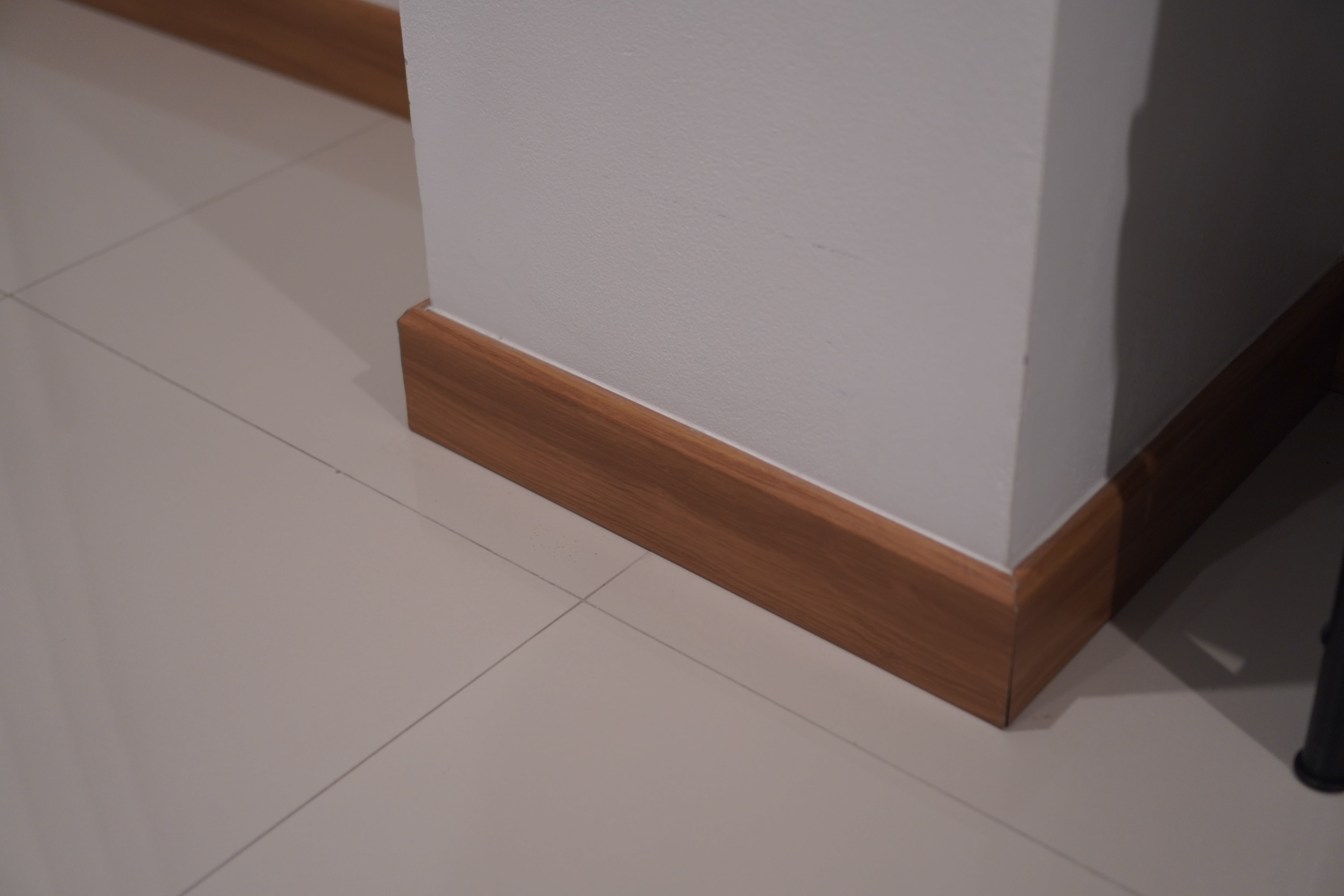 A white wall with a wooden baseboard