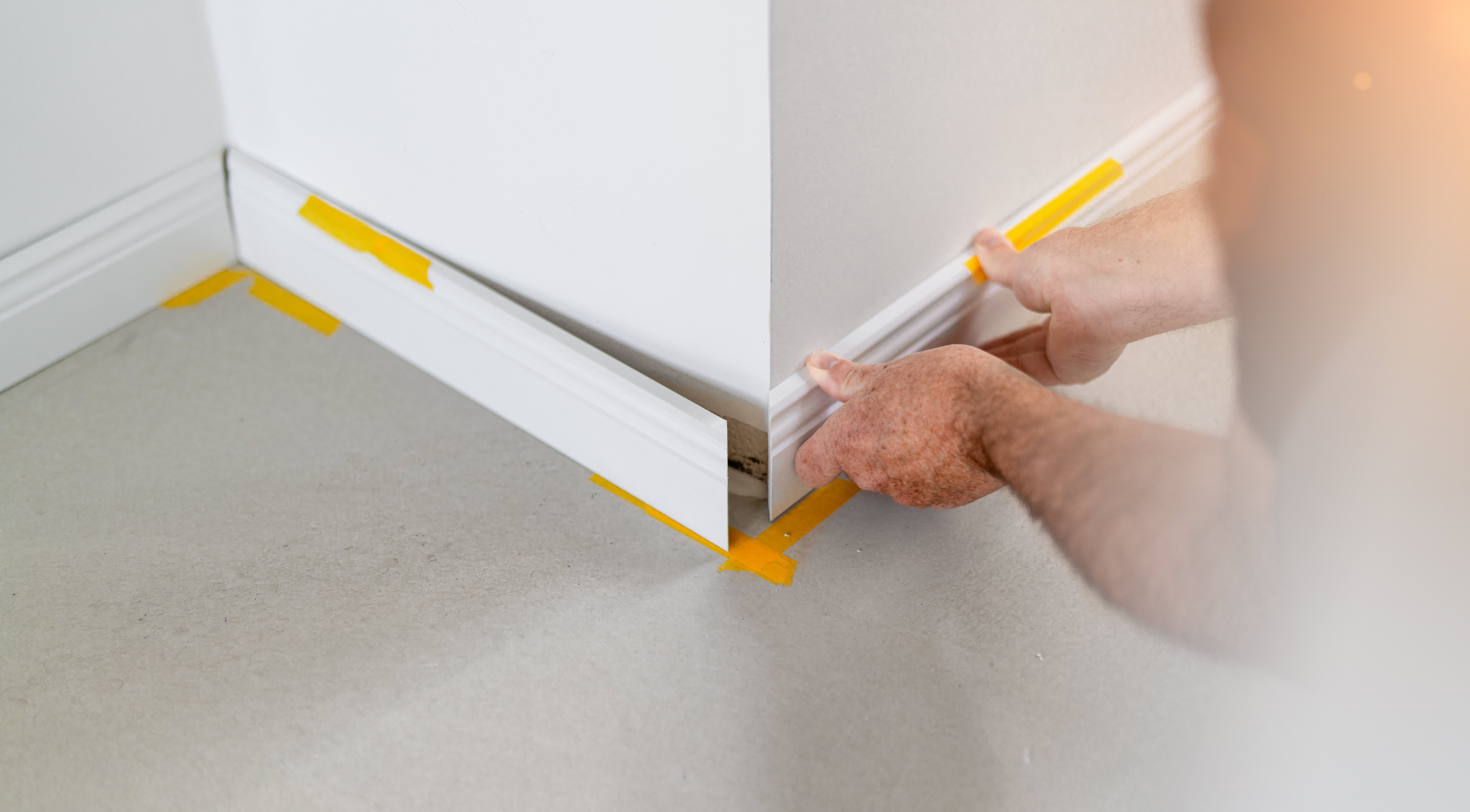 Man installing white baseboard