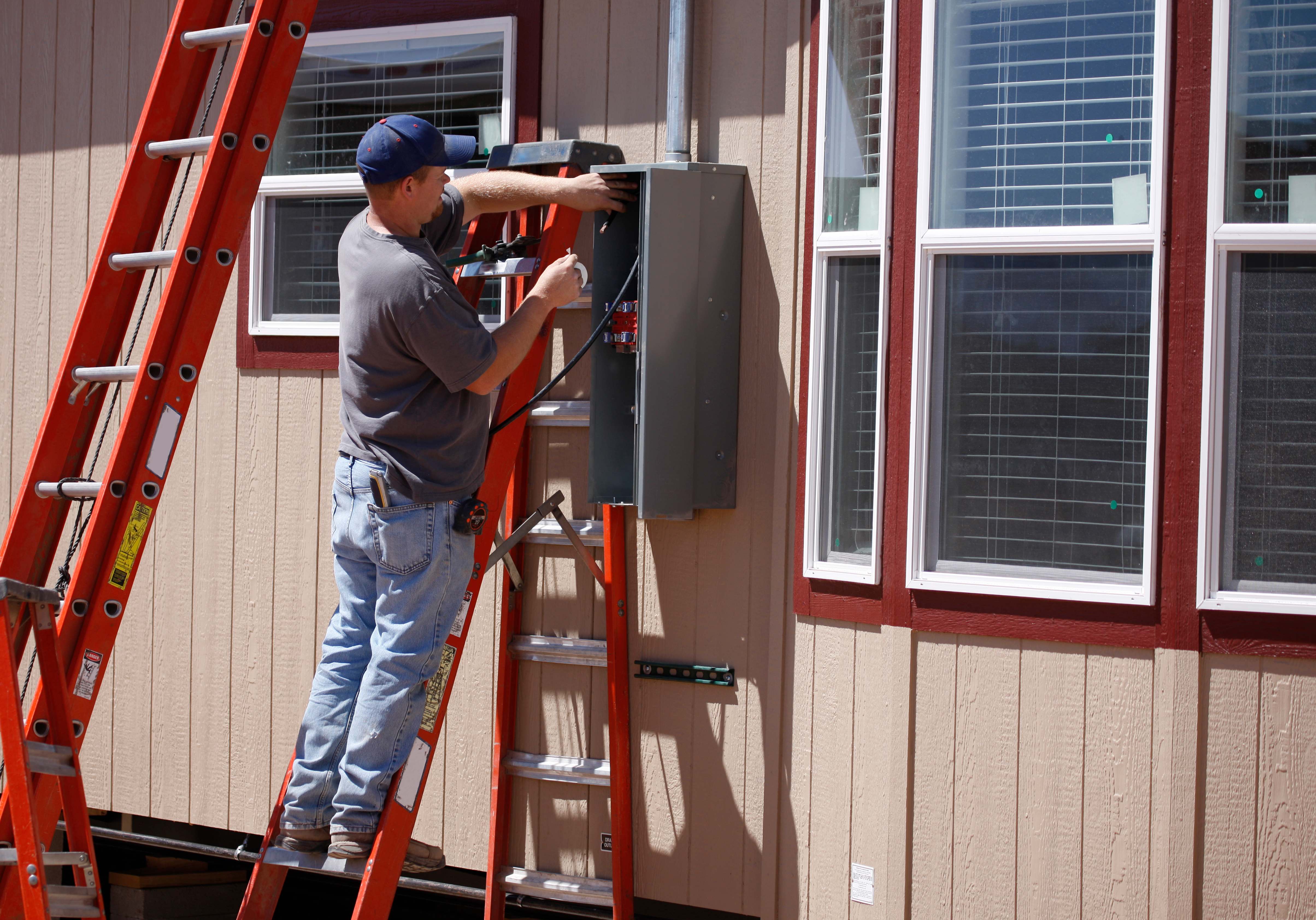 Electrician installing a new electrical box outside the house