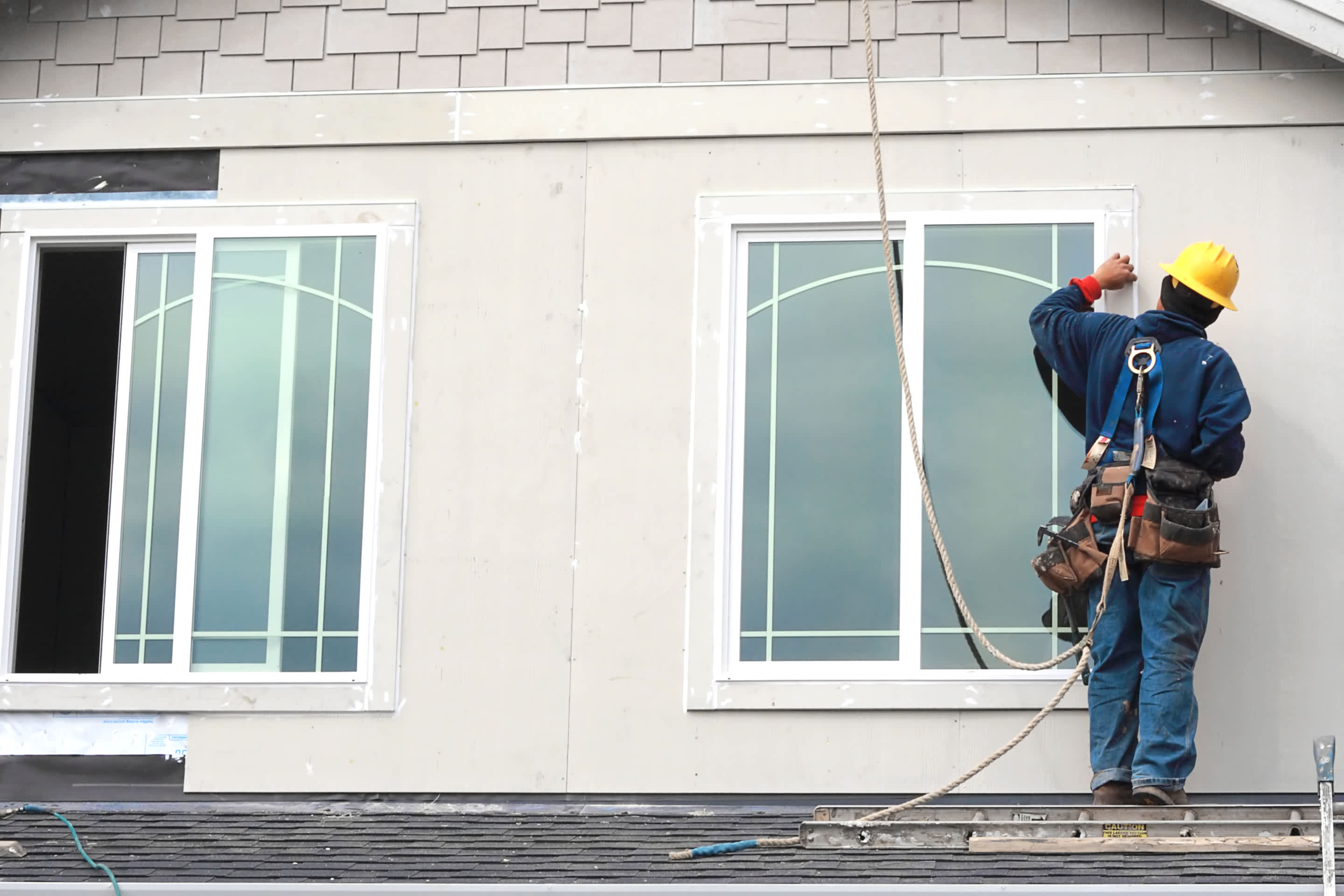 Contractor wearing a safety harness installing new windows