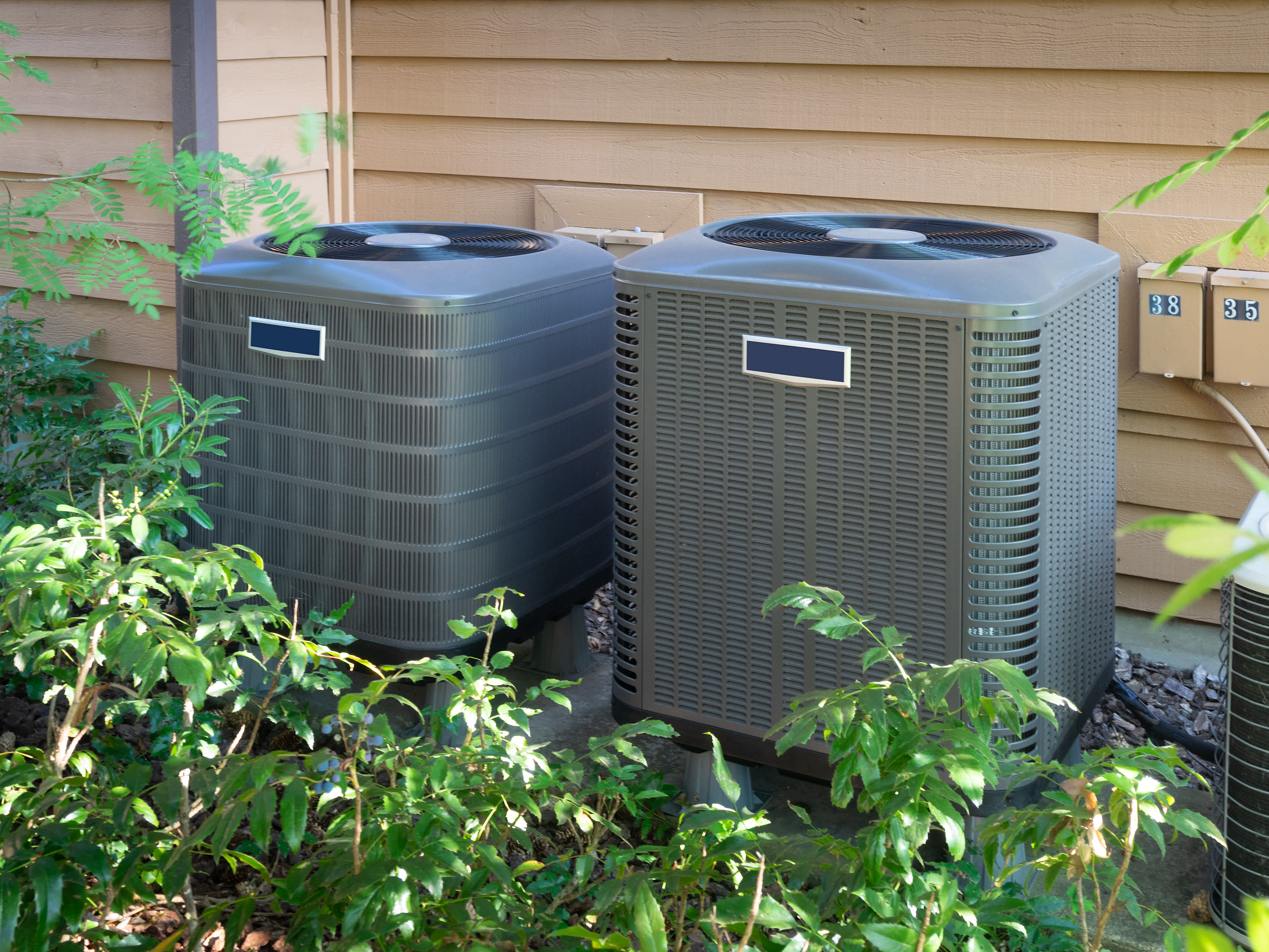 Two central air units outside an apartment complex