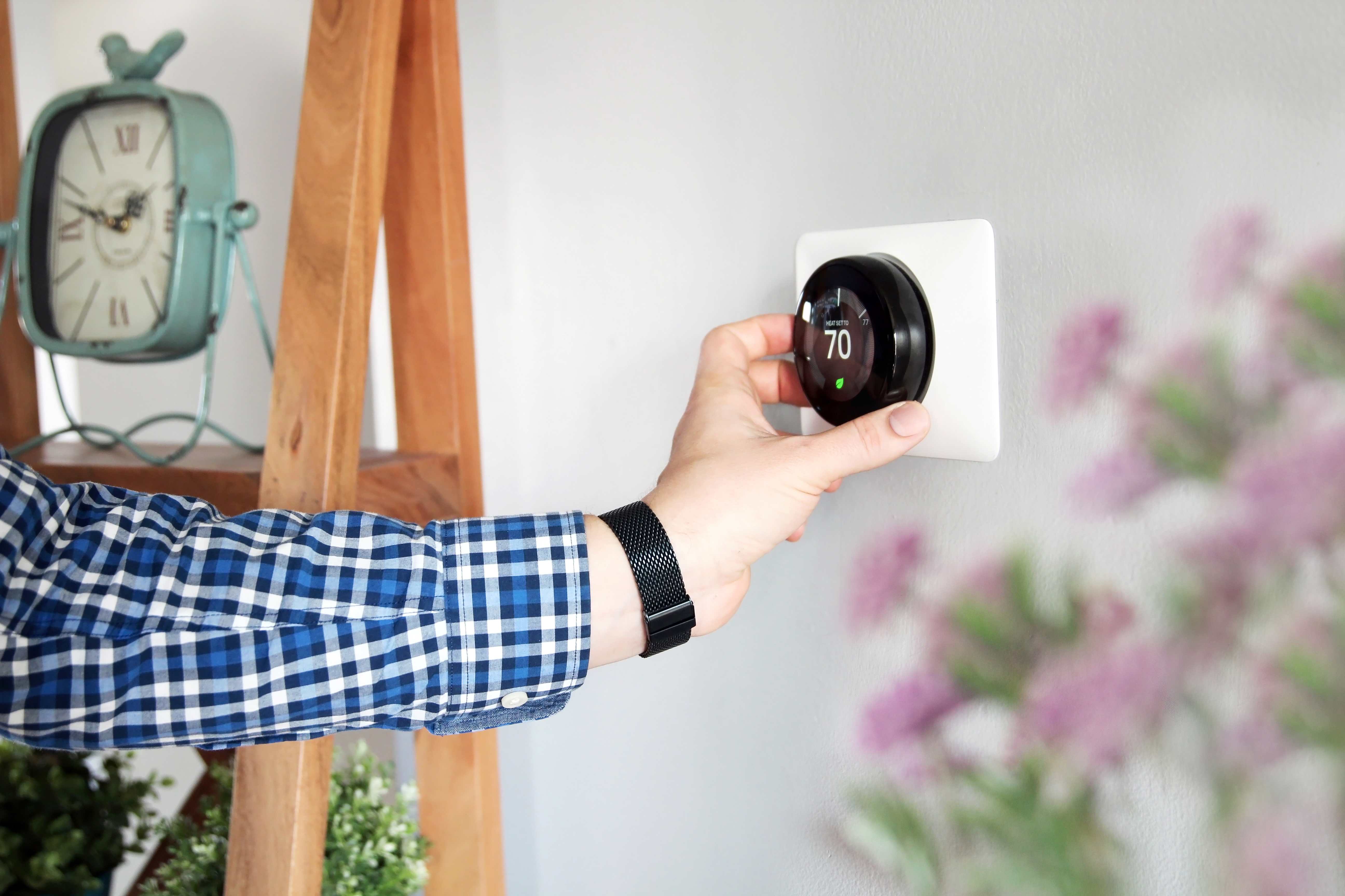 Person adjusting room temperature on a thermostat