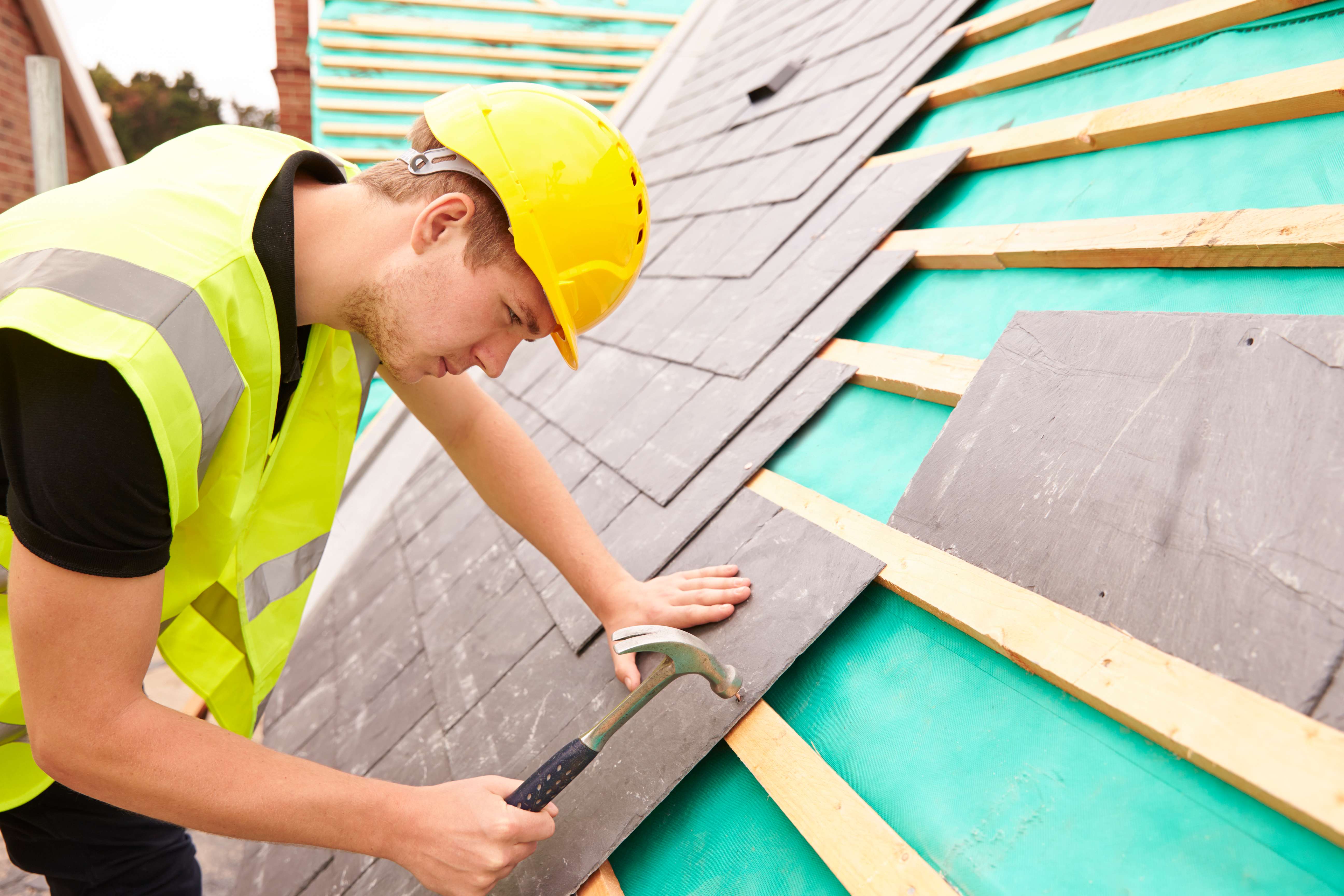 Worker installing slate shingles on the roof