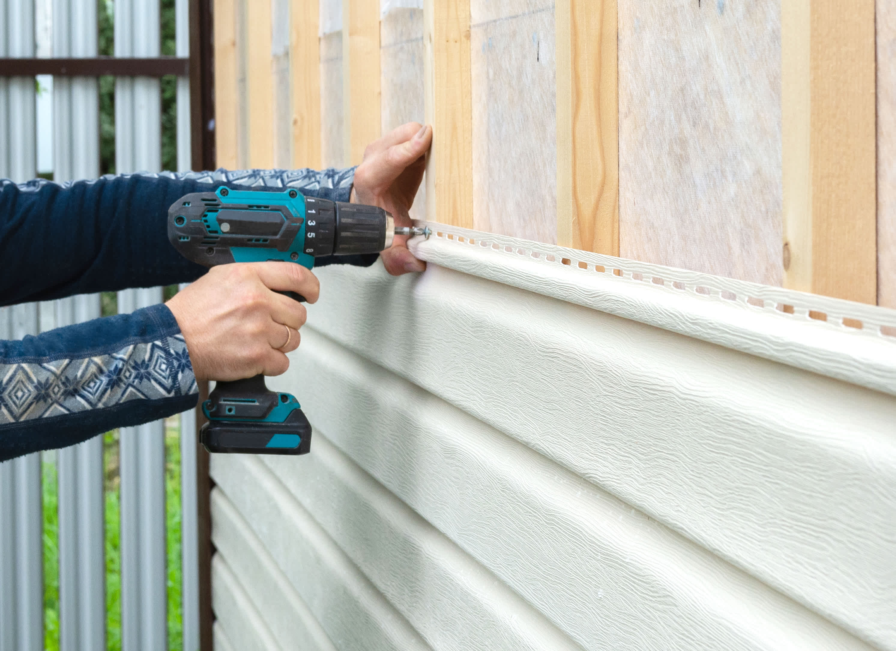 Worker attaching new vinyl siding to the house