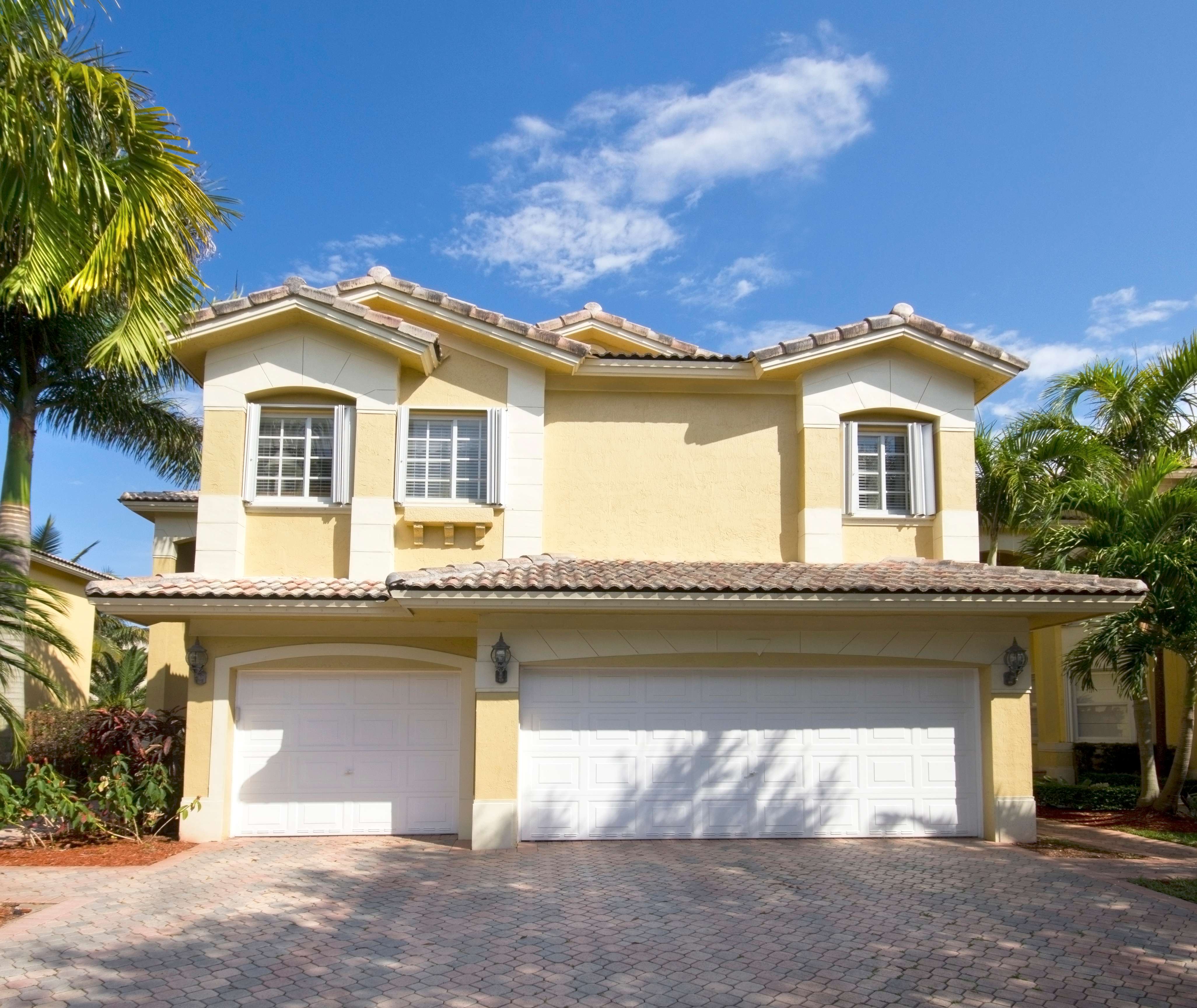 Coastal house exterior with a garage and palm trees