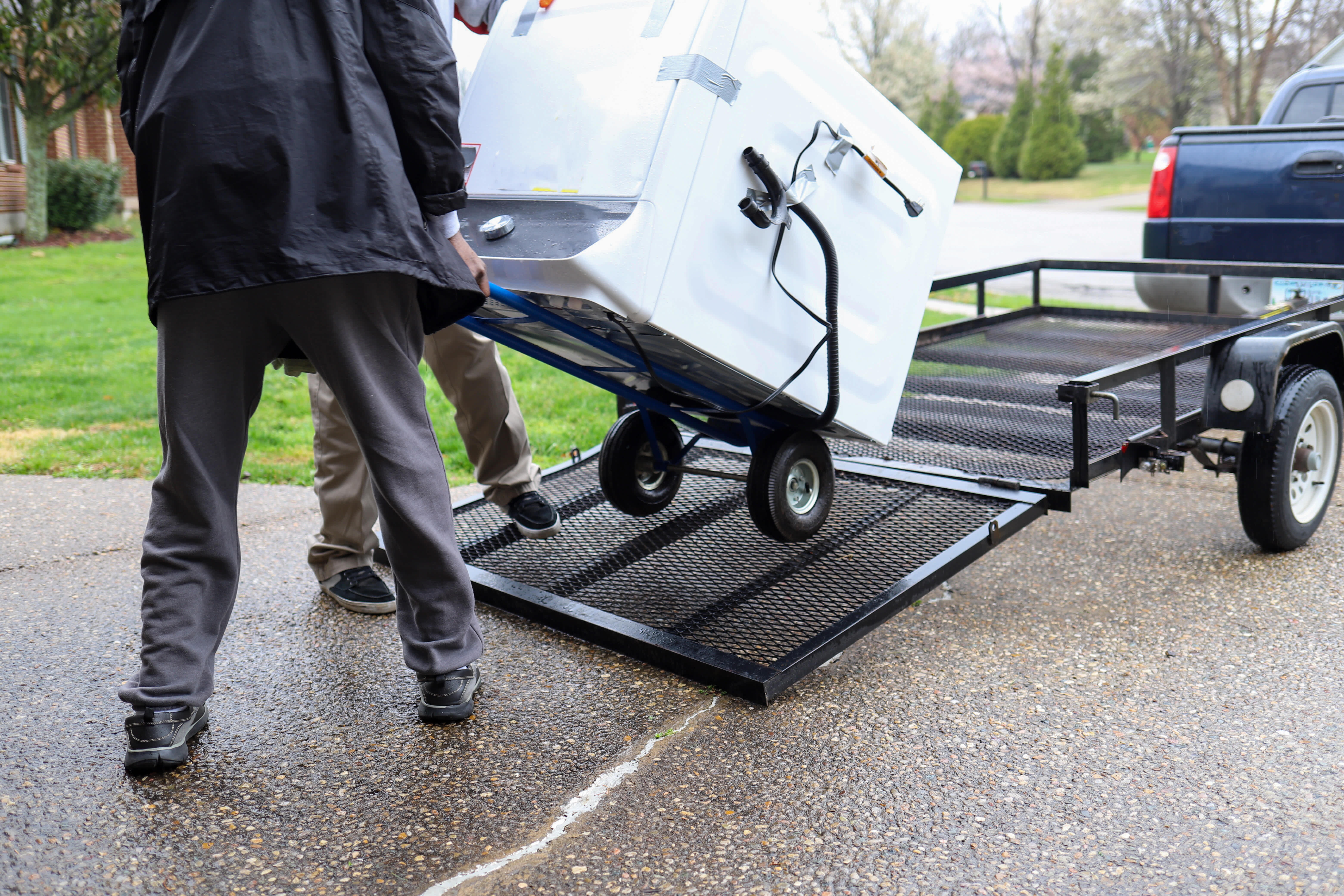 Man hauling a washing machine, showcasing appliance removal for replacement, disposal, or relocation of heavy household items