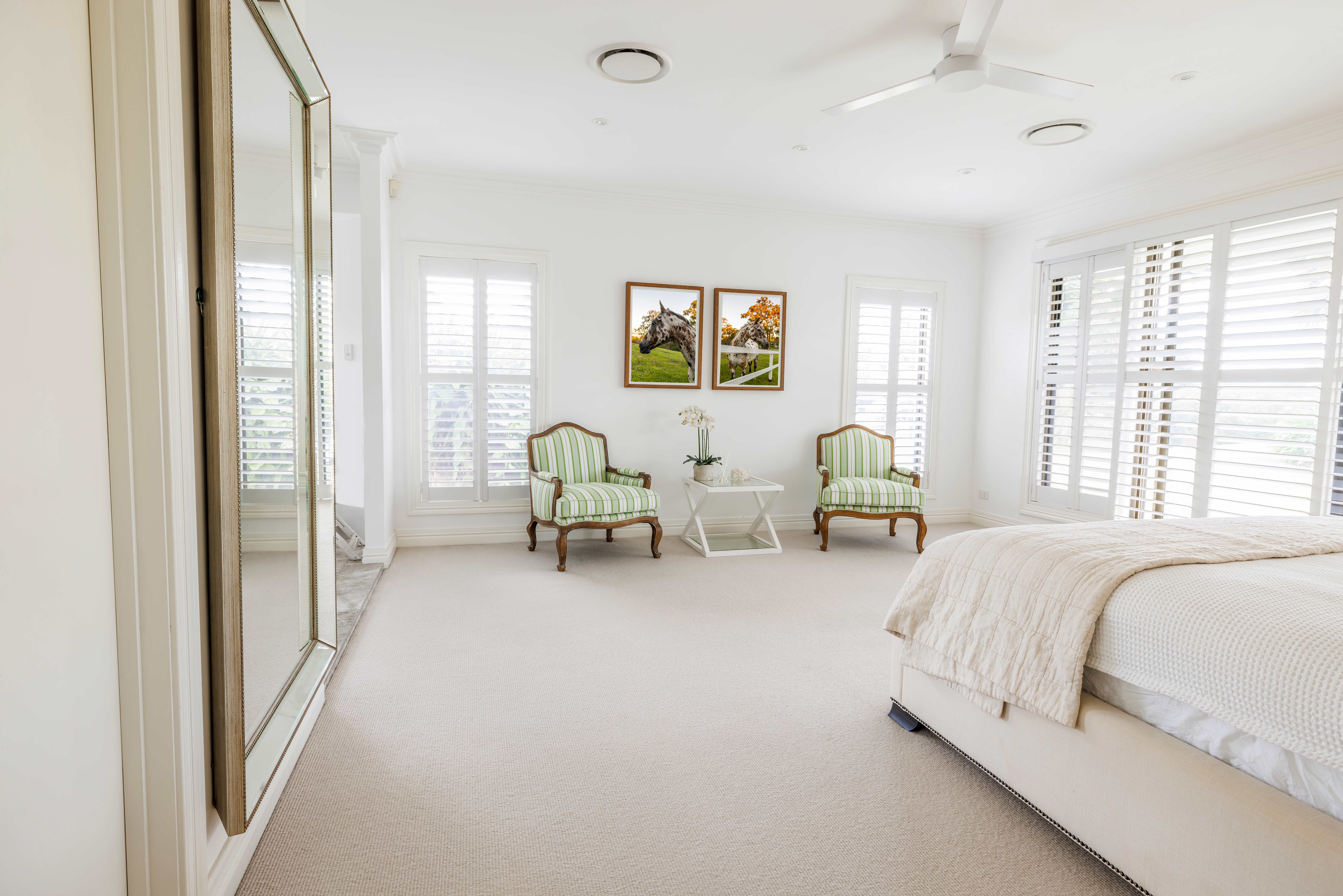 Bright primary bedroom with wool carpet and two green chairs