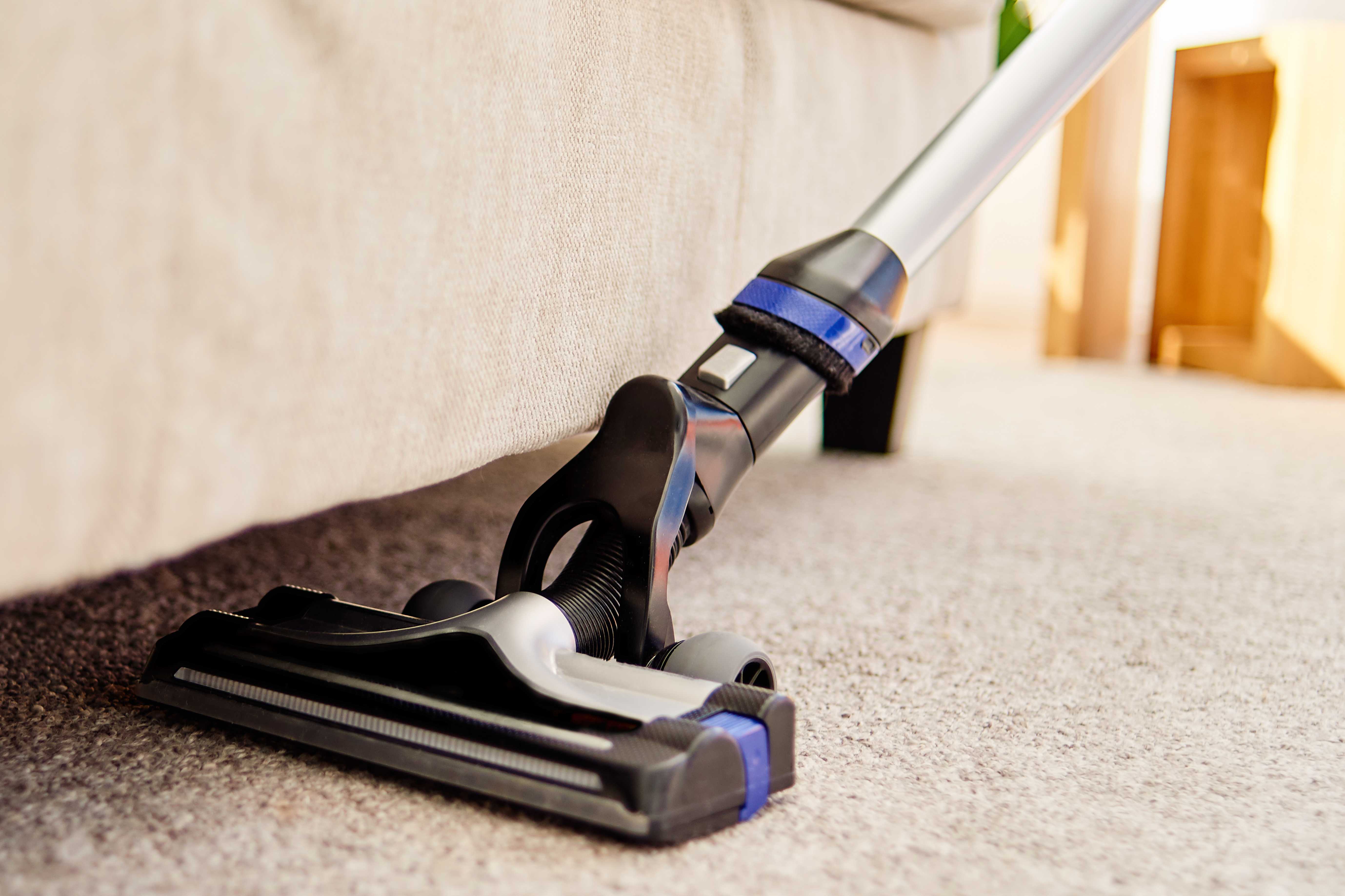 Close-up of a vacuum cleaner cleaning a wool carpet
