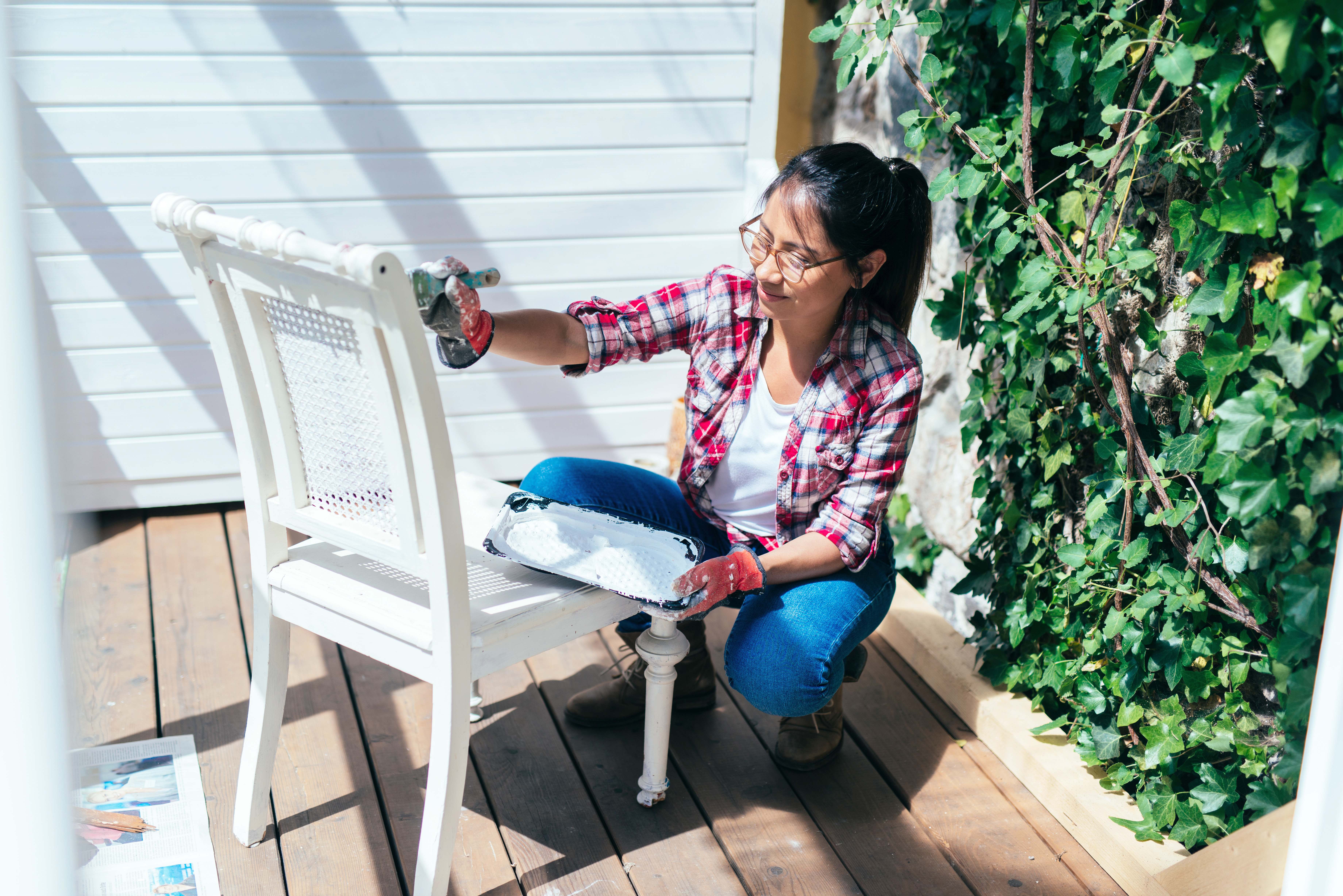 Woman painting a white chair on the patio