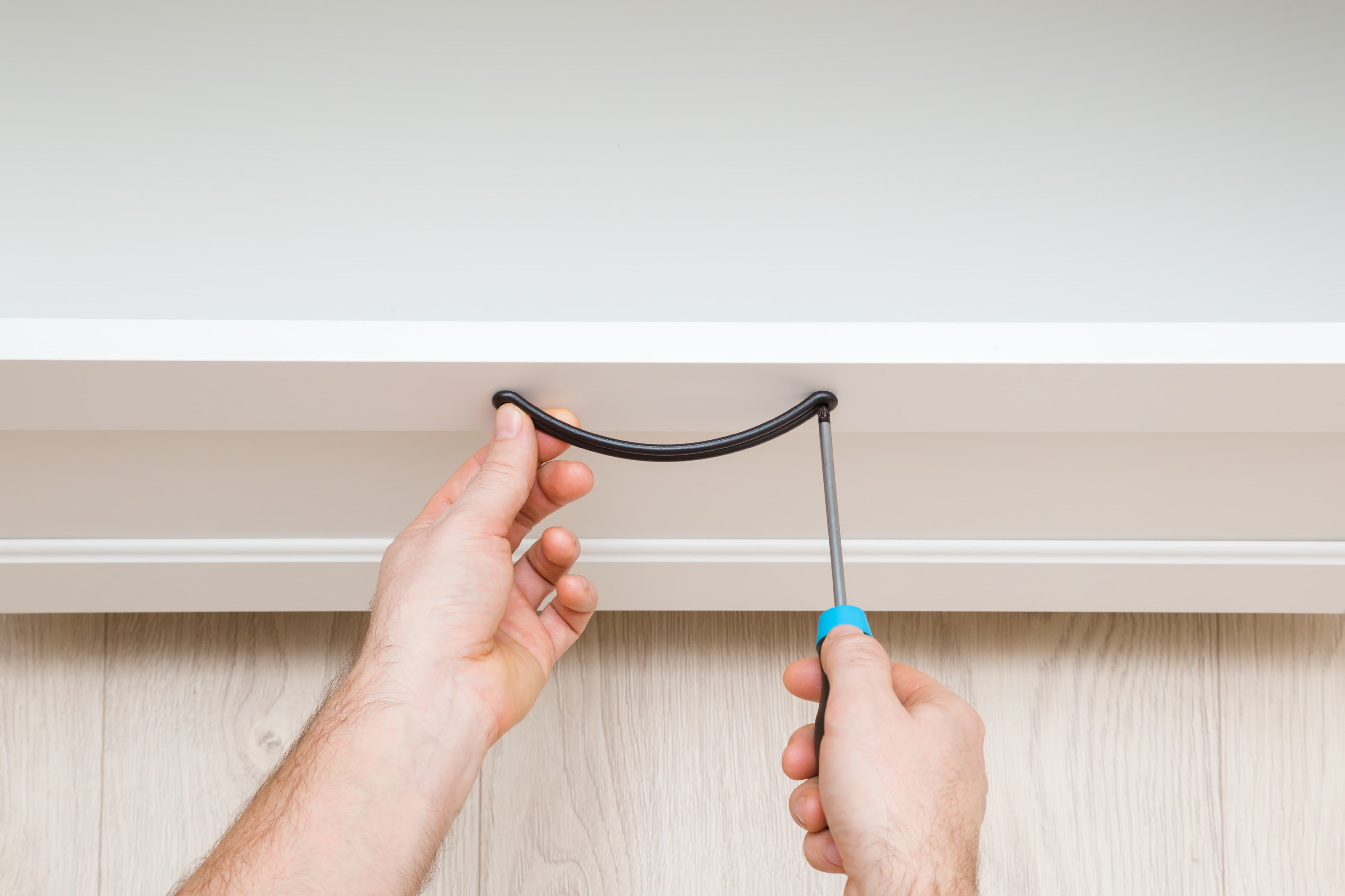 Person using a screwdriver to remove furniture hardware