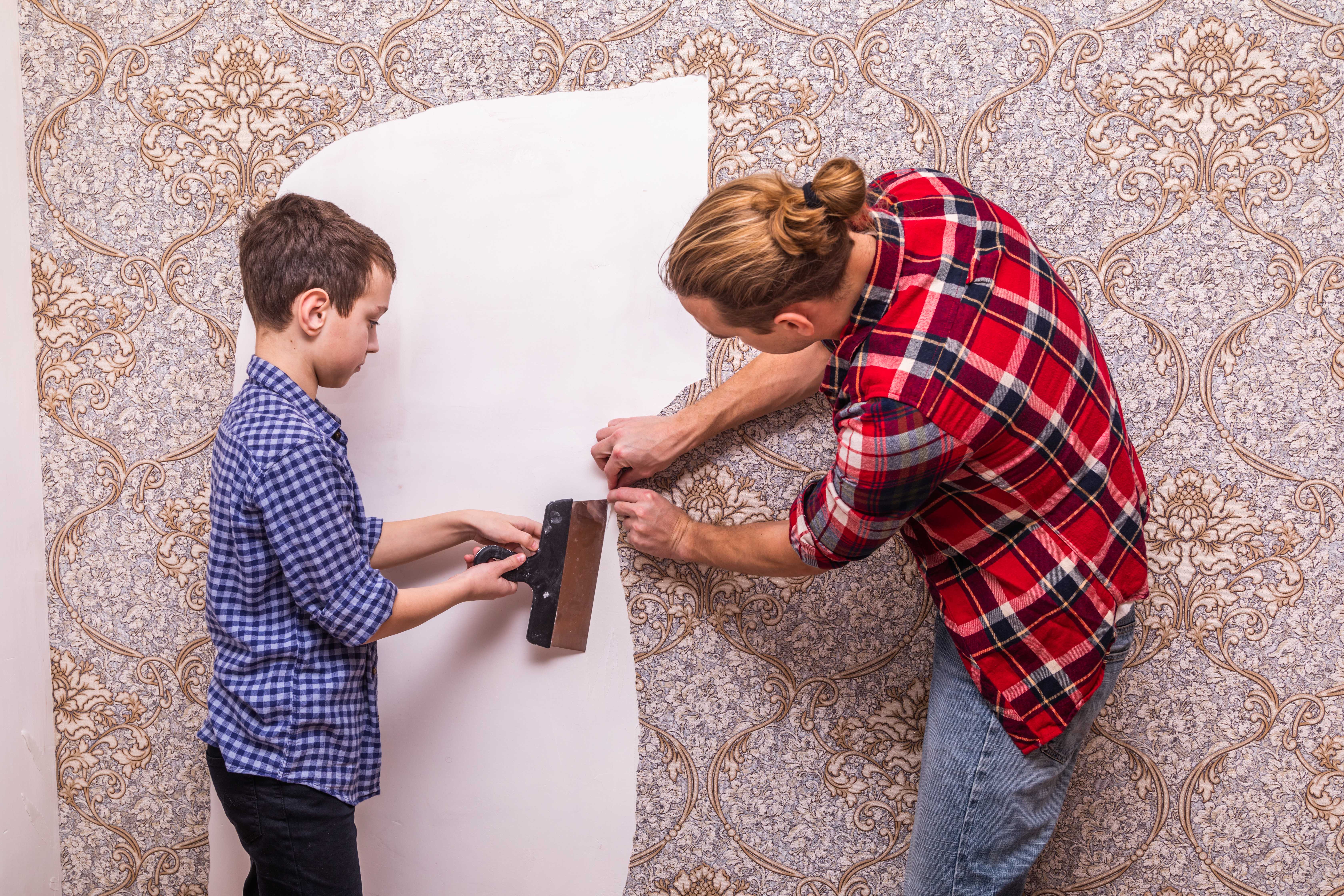 father and son peeling off wallpaper