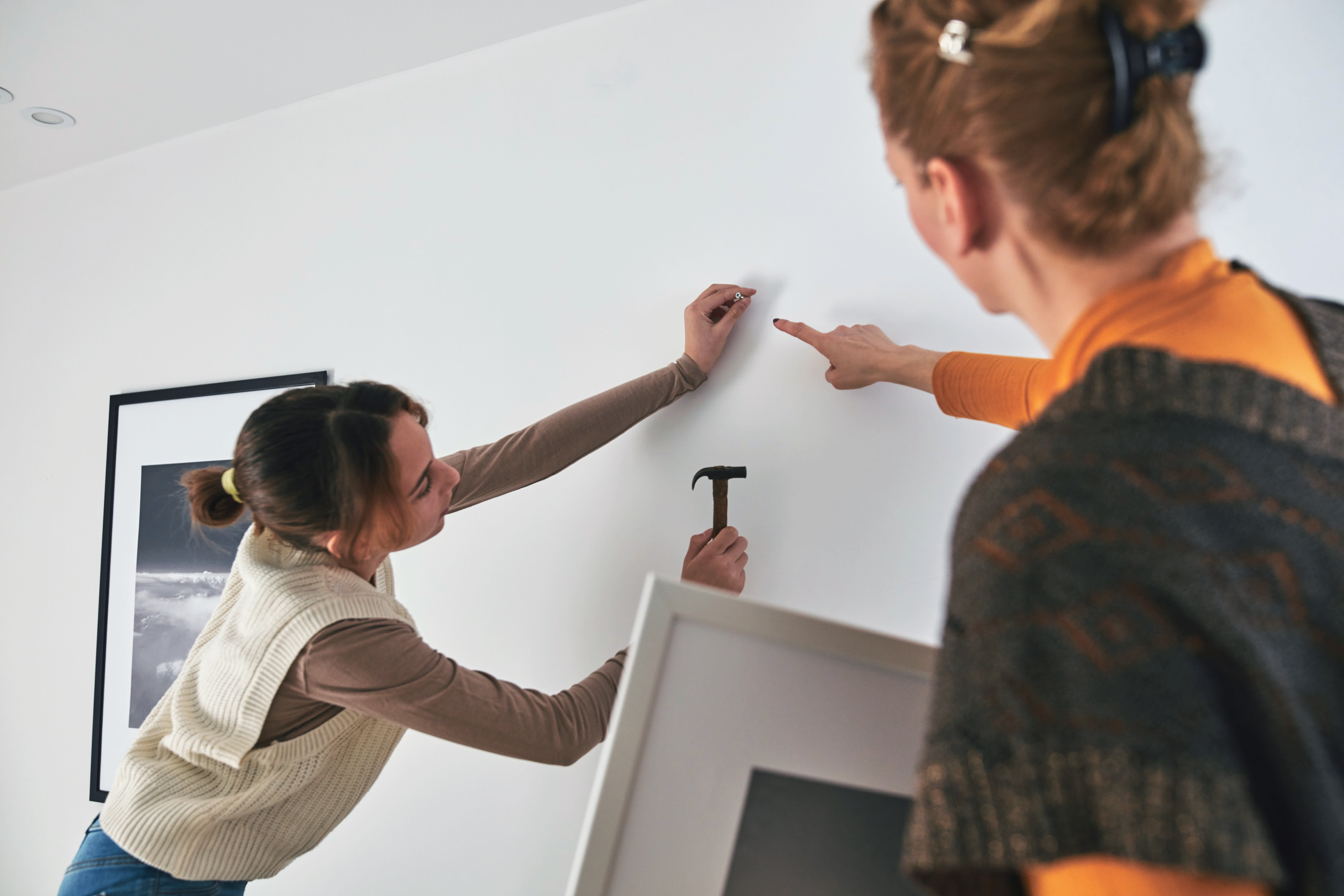 Woman and daughter hanging picture