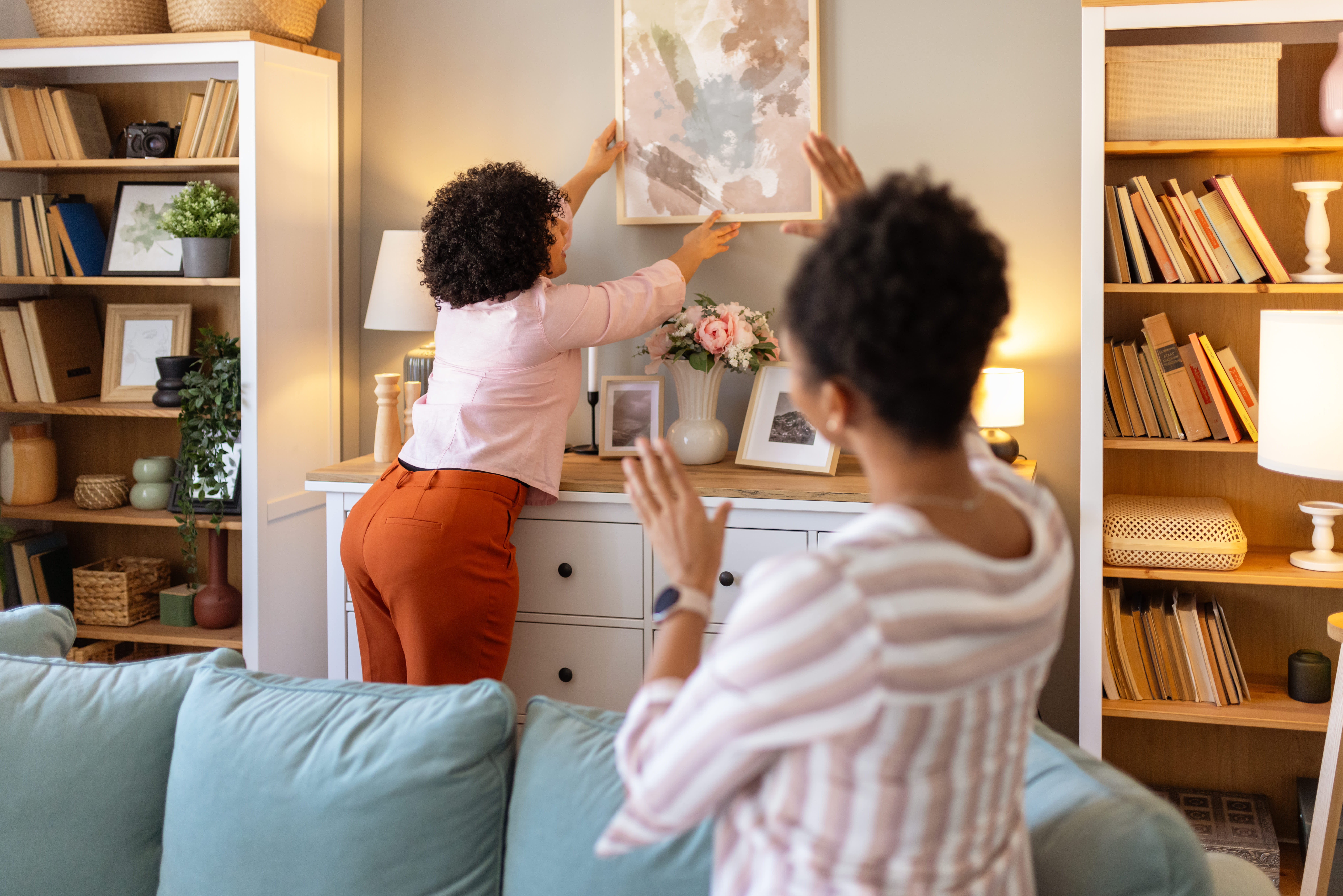 Women lining up picture on wall