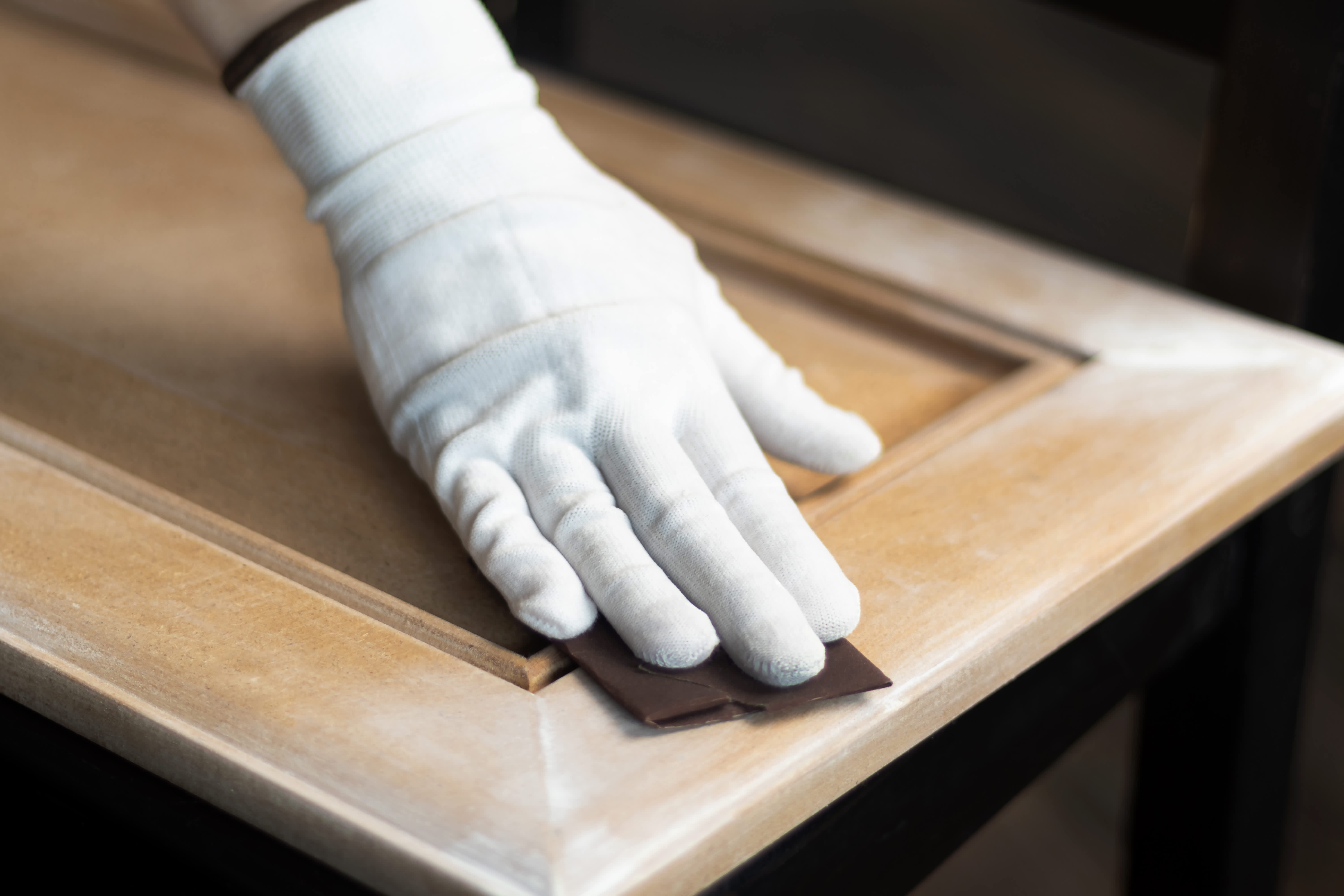 Man sanding a wooden cabinet
