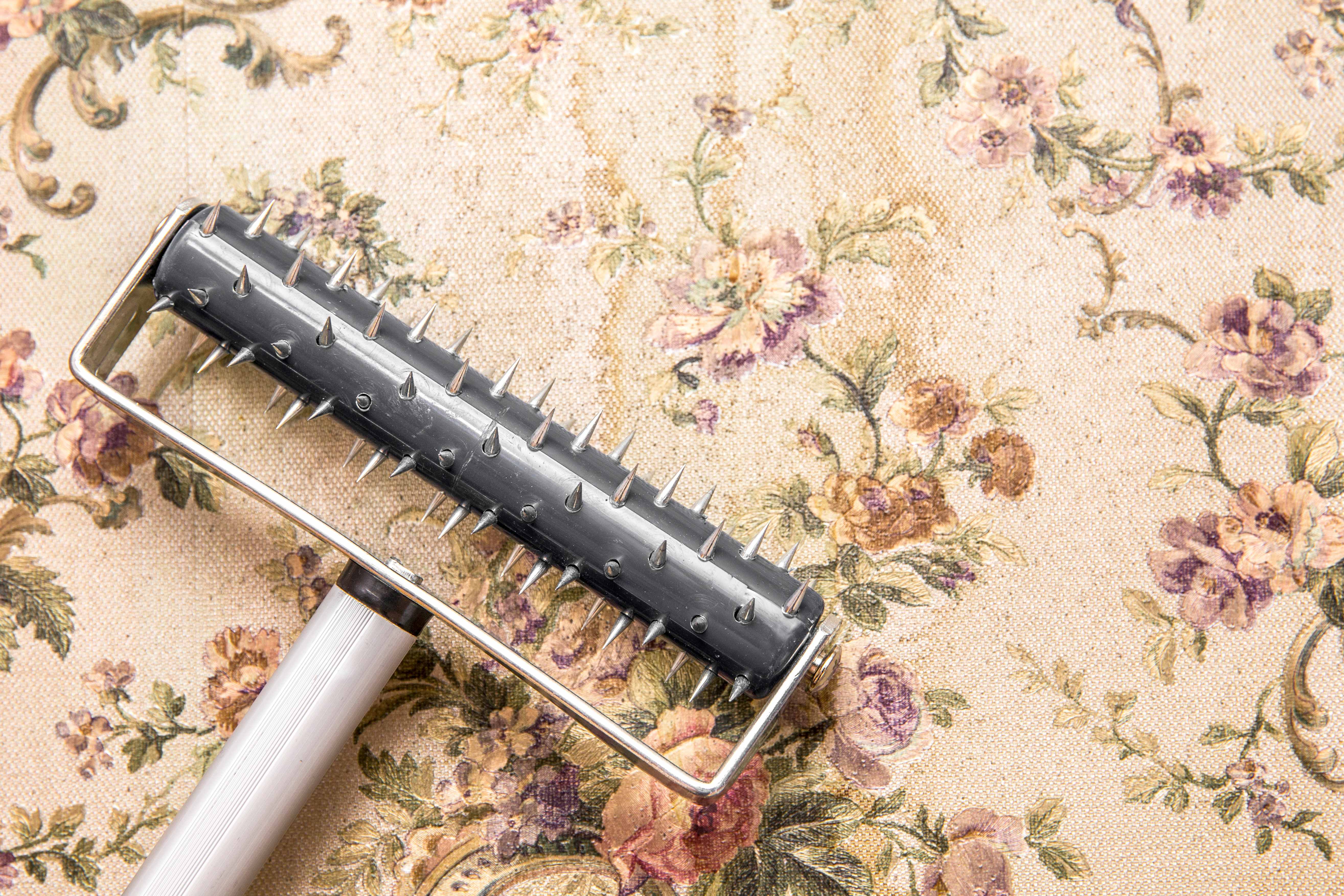 Using a scoring tool to remove old wallpaper from the wall
