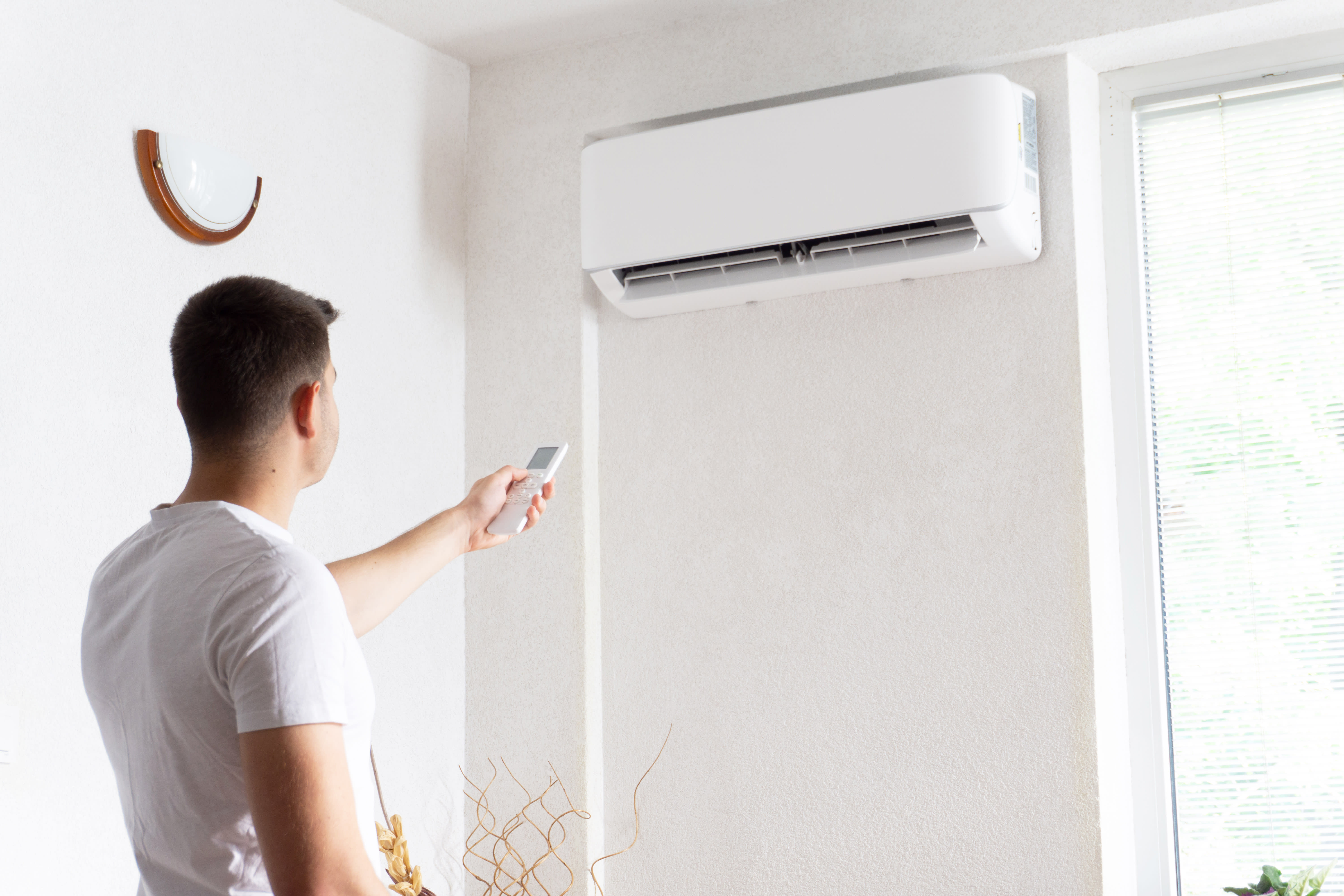 Man using remote to turn mini-split AC on