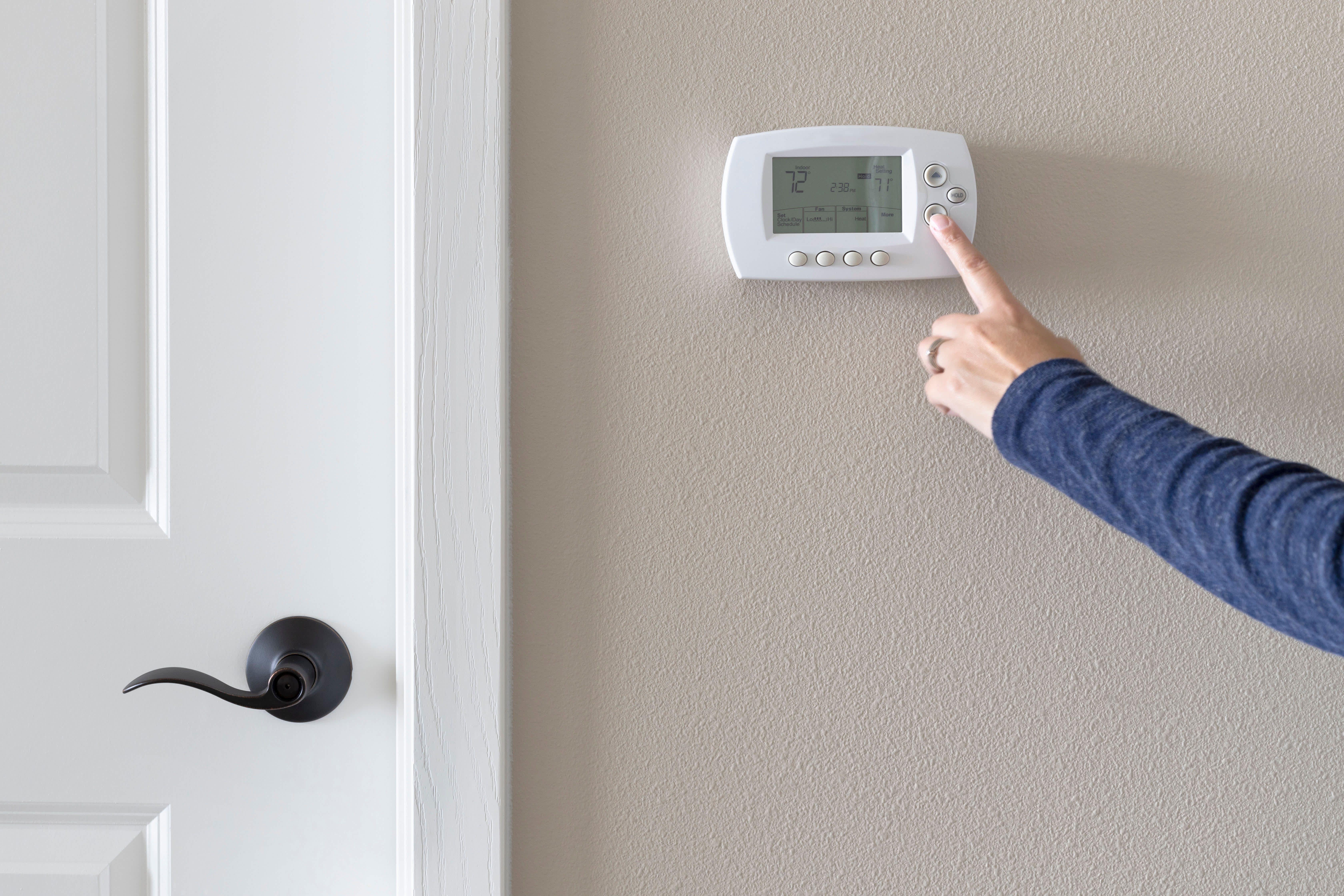 Person using programmable thermostat to turn AC on