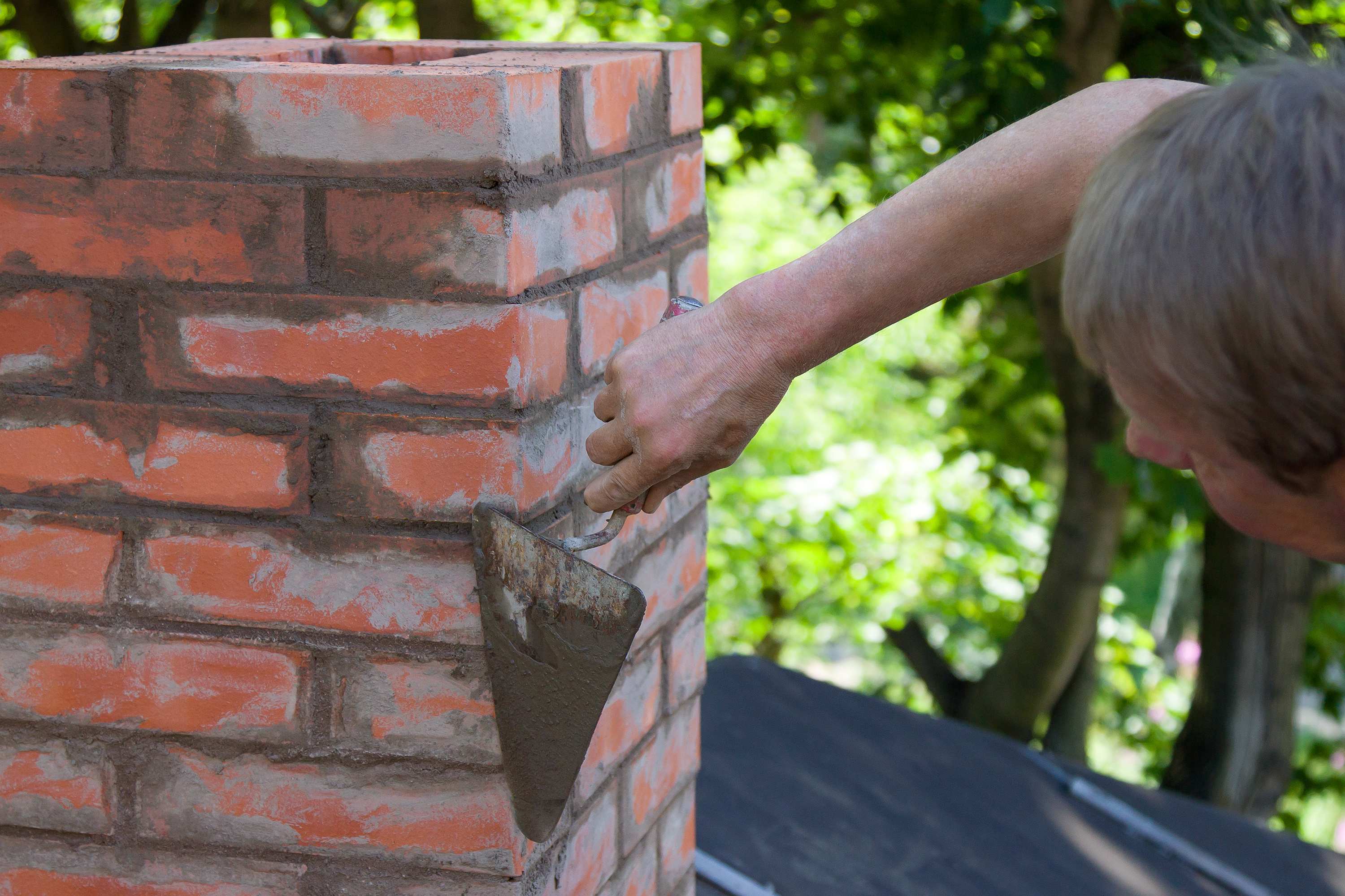 man apply mortar to chimney